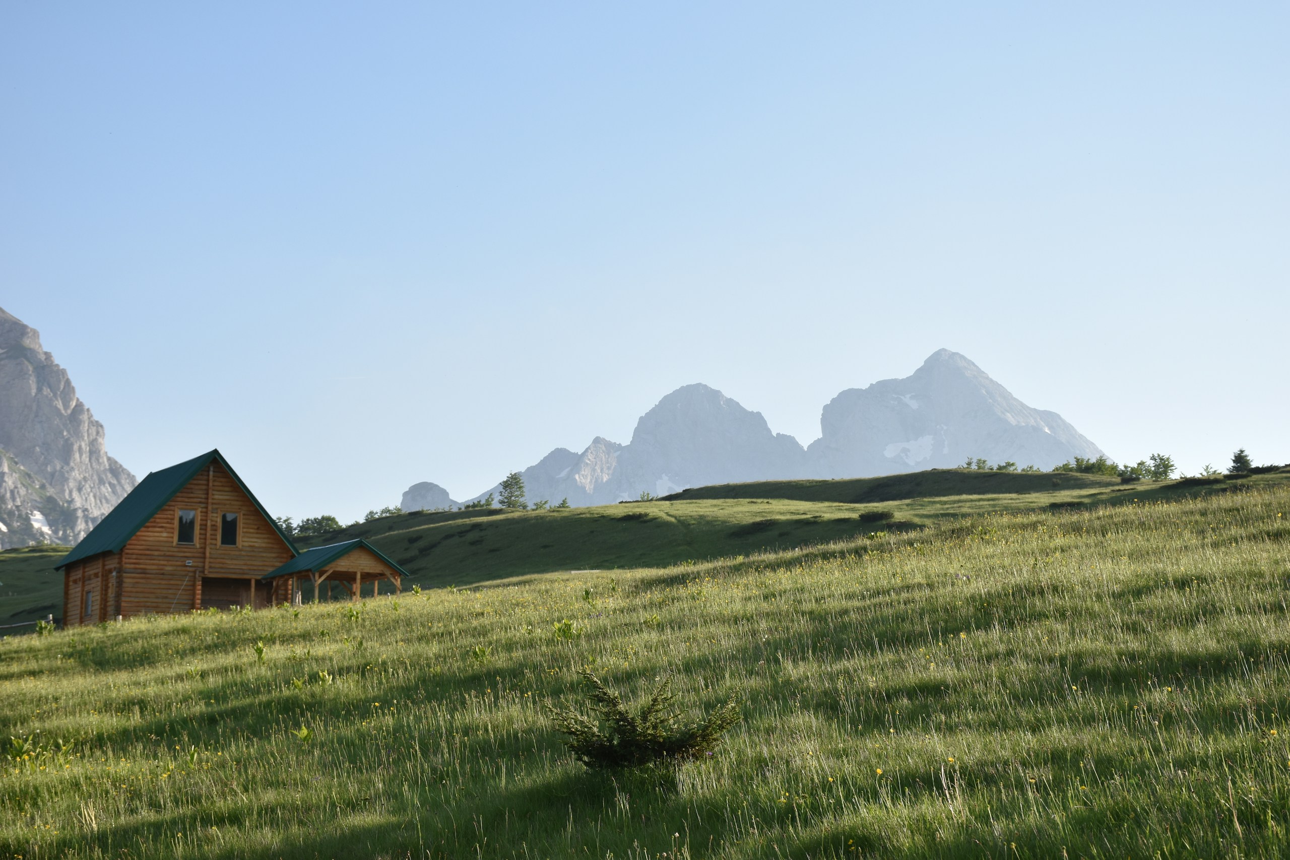 Log cabin in a grassy mountain landscape HD Wallpaper