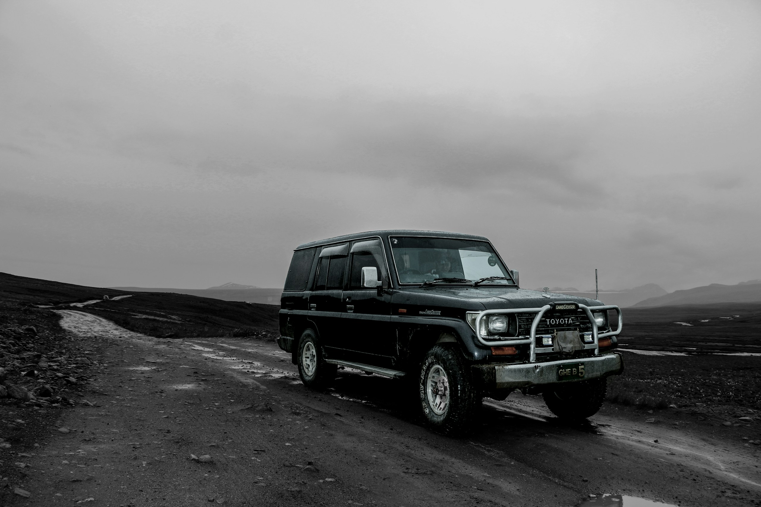 Black Toyota Land Cruiser on a dirt road in a desolate landscape HD Wallpaper
