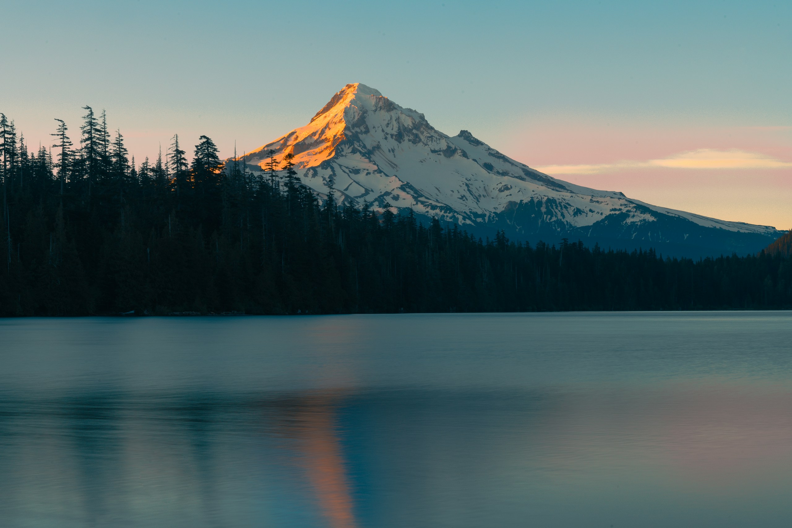 Snow-capped mountain reflected in a calm lake at sunset HD Wallpaper