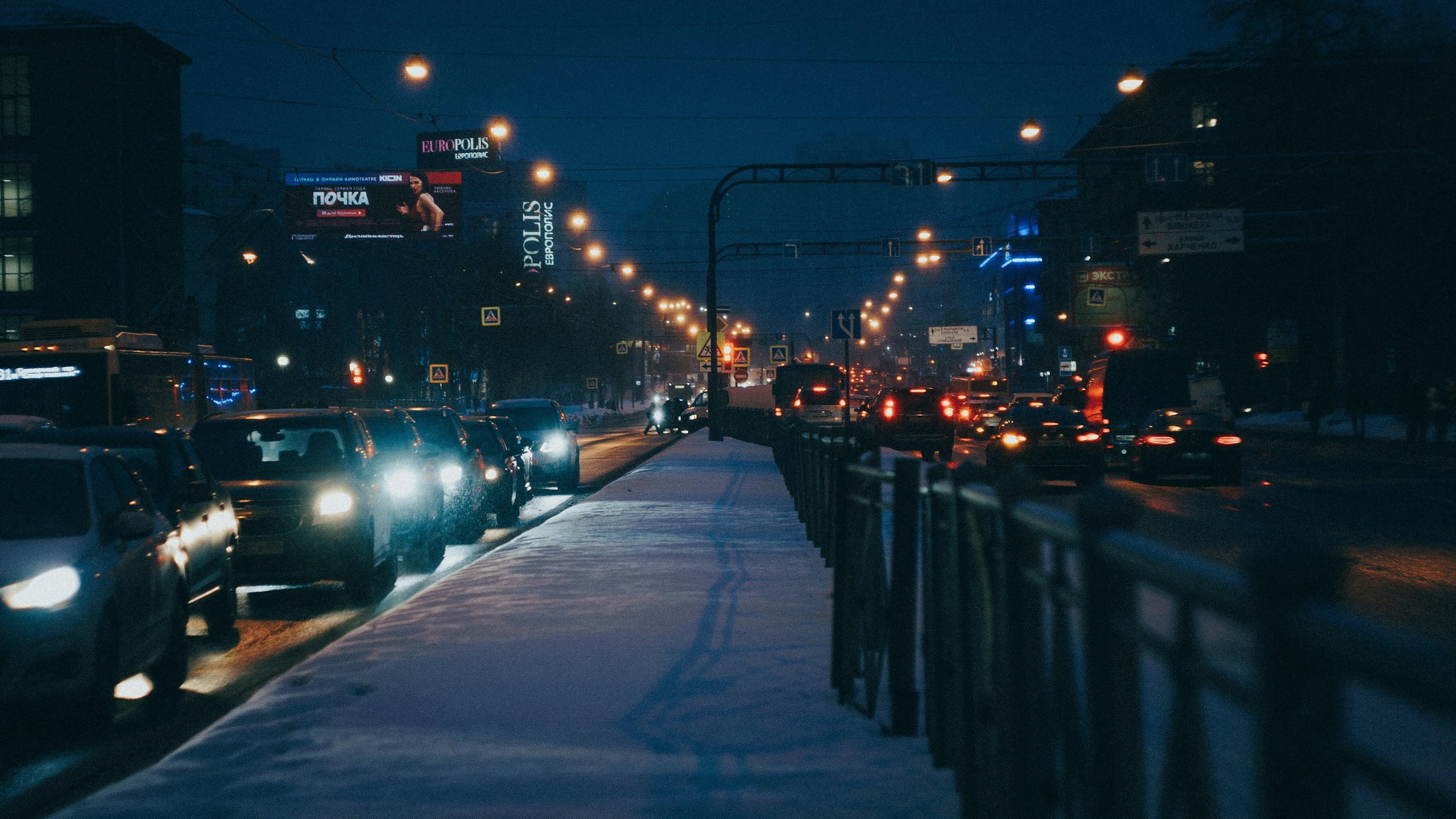 Snowy city street at night with traffic HD Wallpaper