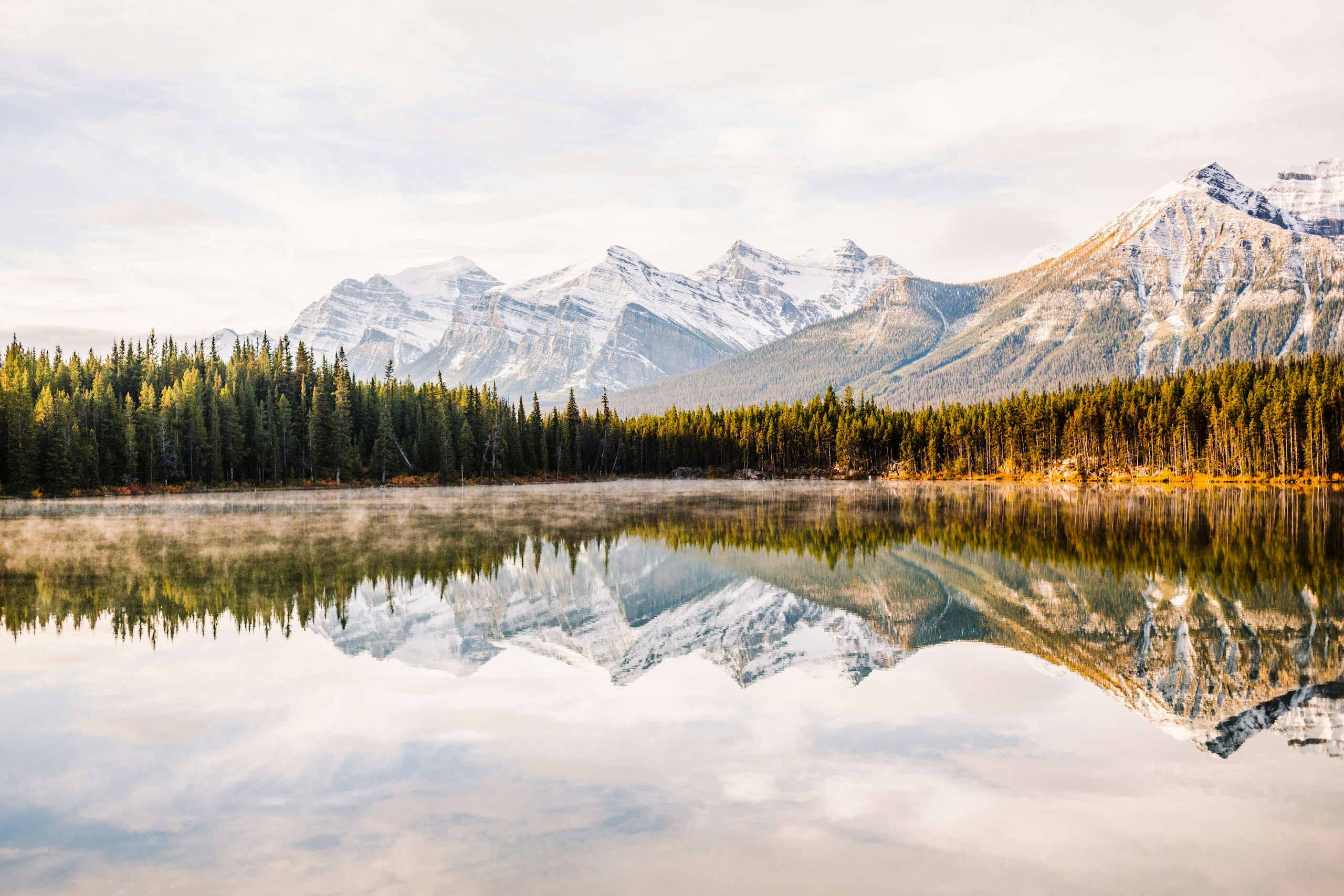 Snow-capped mountains reflected in a calm lake HD Wallpaper
