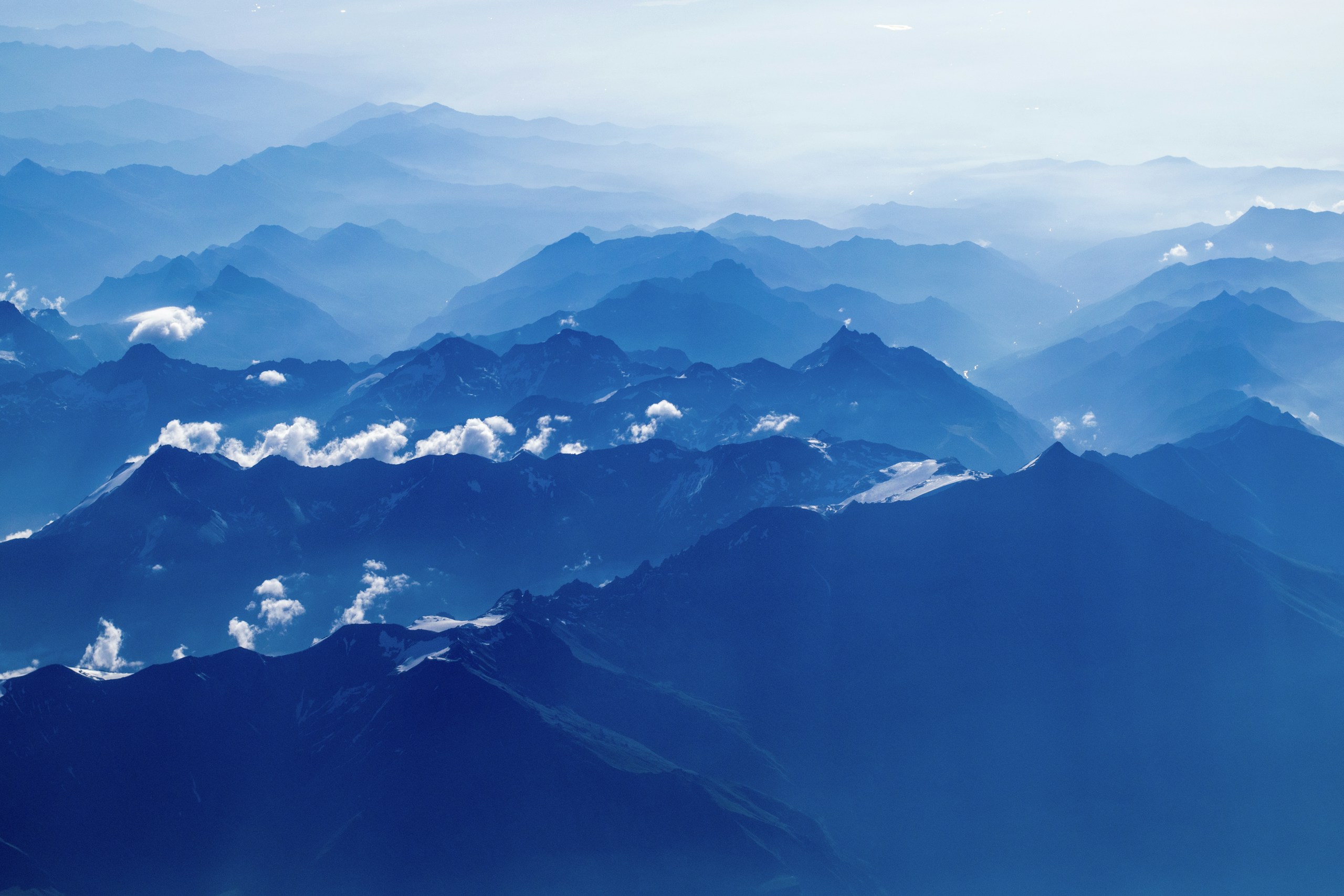 Aerial view of layered blue mountains and clouds HD Wallpaper
