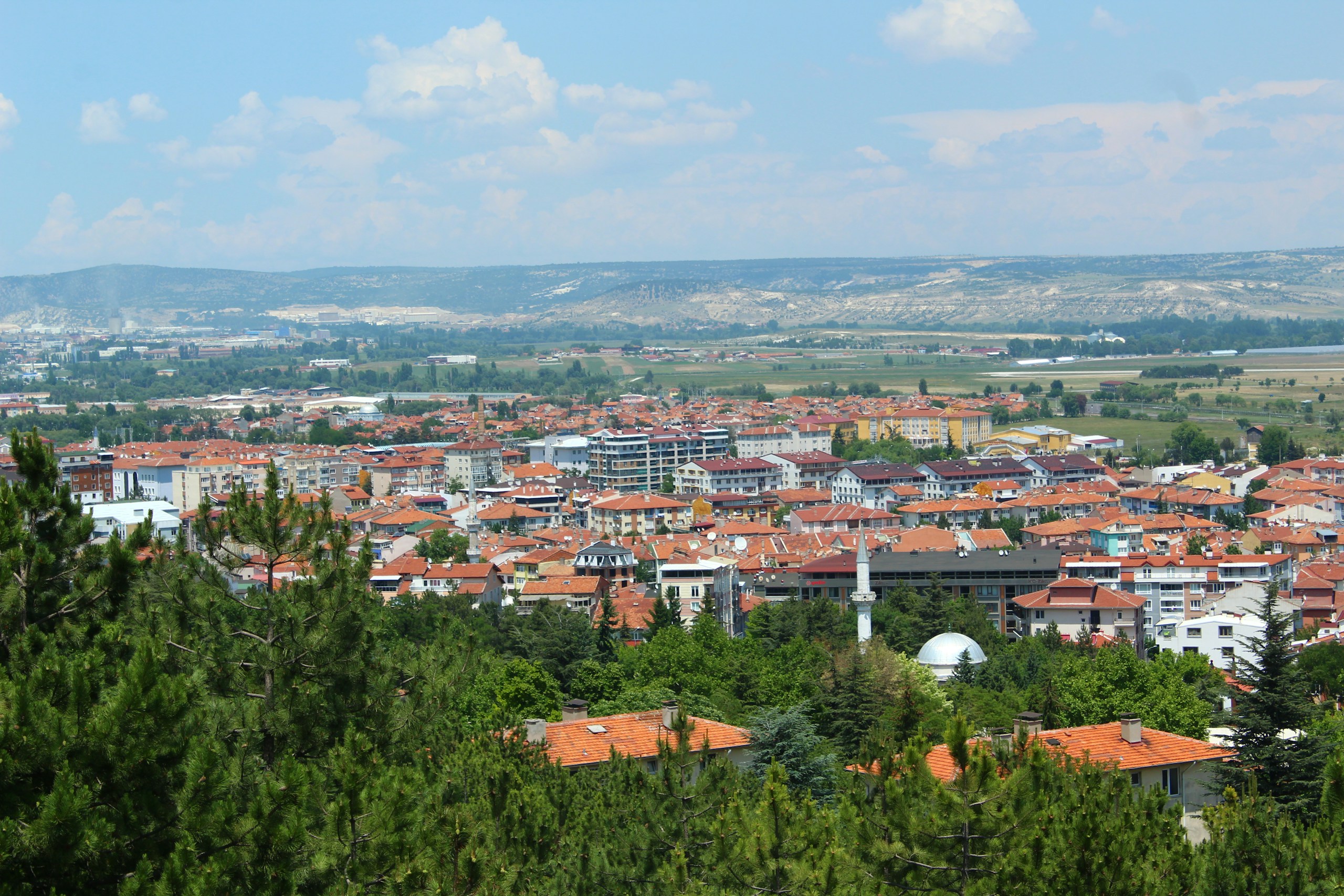 Aerial view of a city with red-tiled roofs and distant hills HD Wallpaper