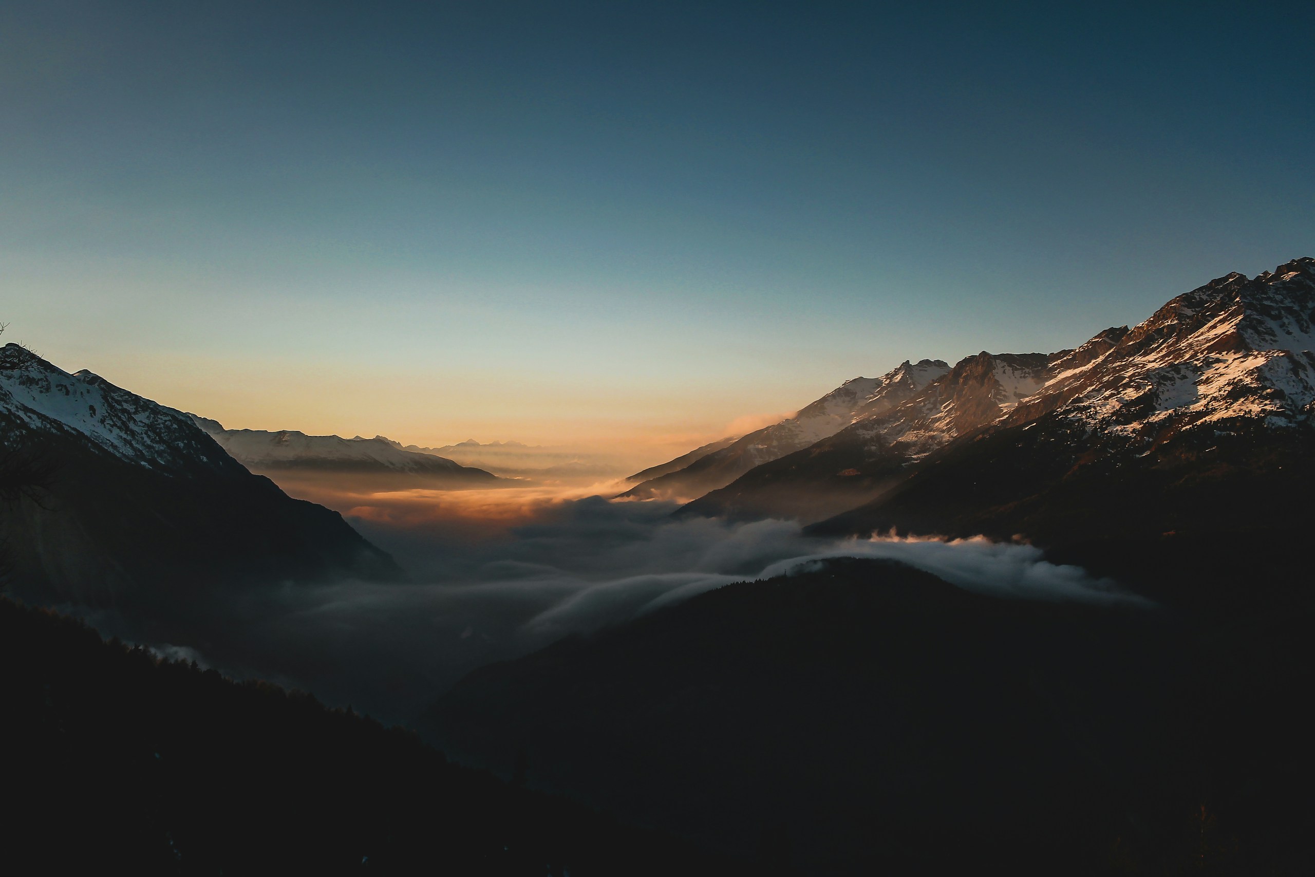 Mountain range at sunrise with clouds below HD Wallpaper