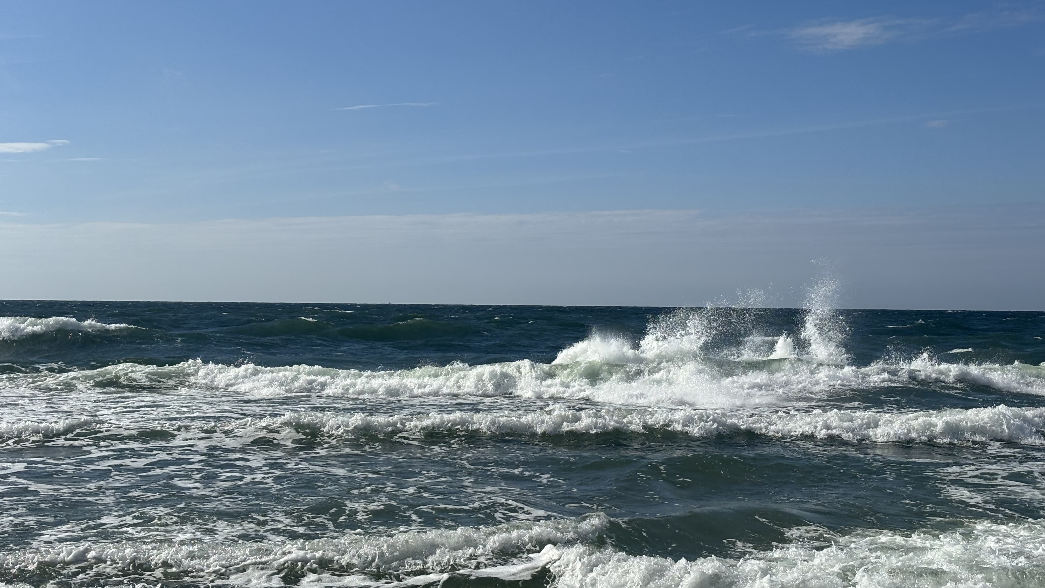 Ocean waves crashing under a clear blue sky HD Wallpaper