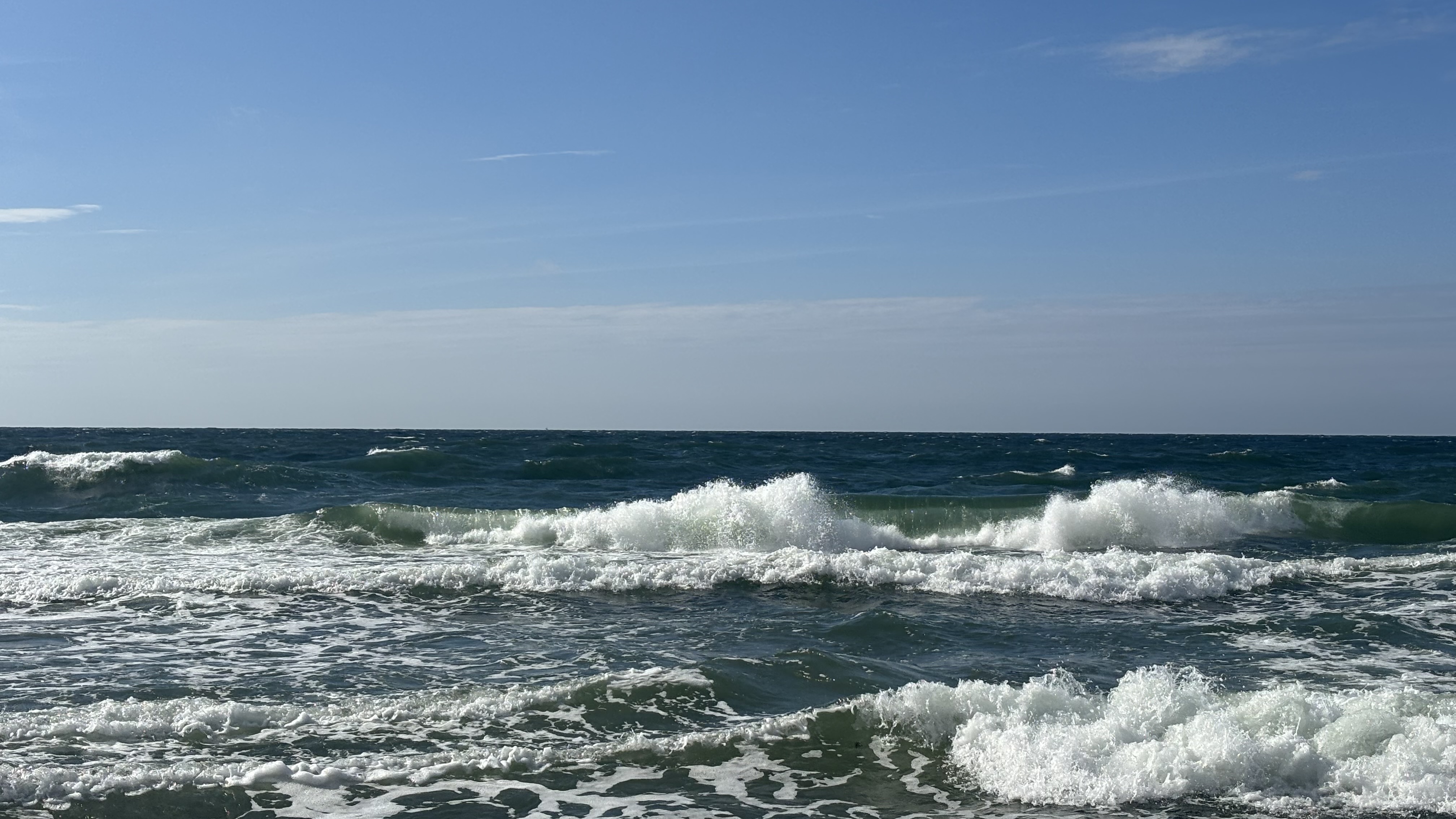 Ocean waves crashing under a clear blue sky HD Wallpaper