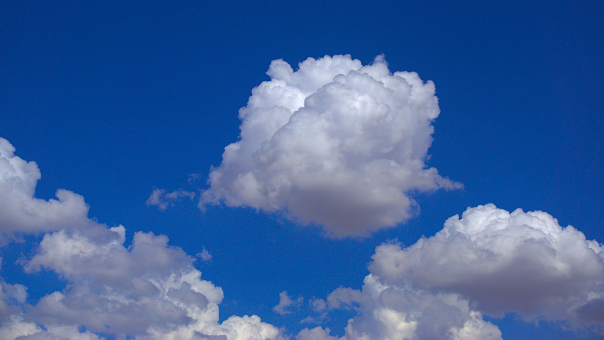 Fluffy white clouds against a bright blue sky HD Wallpaper