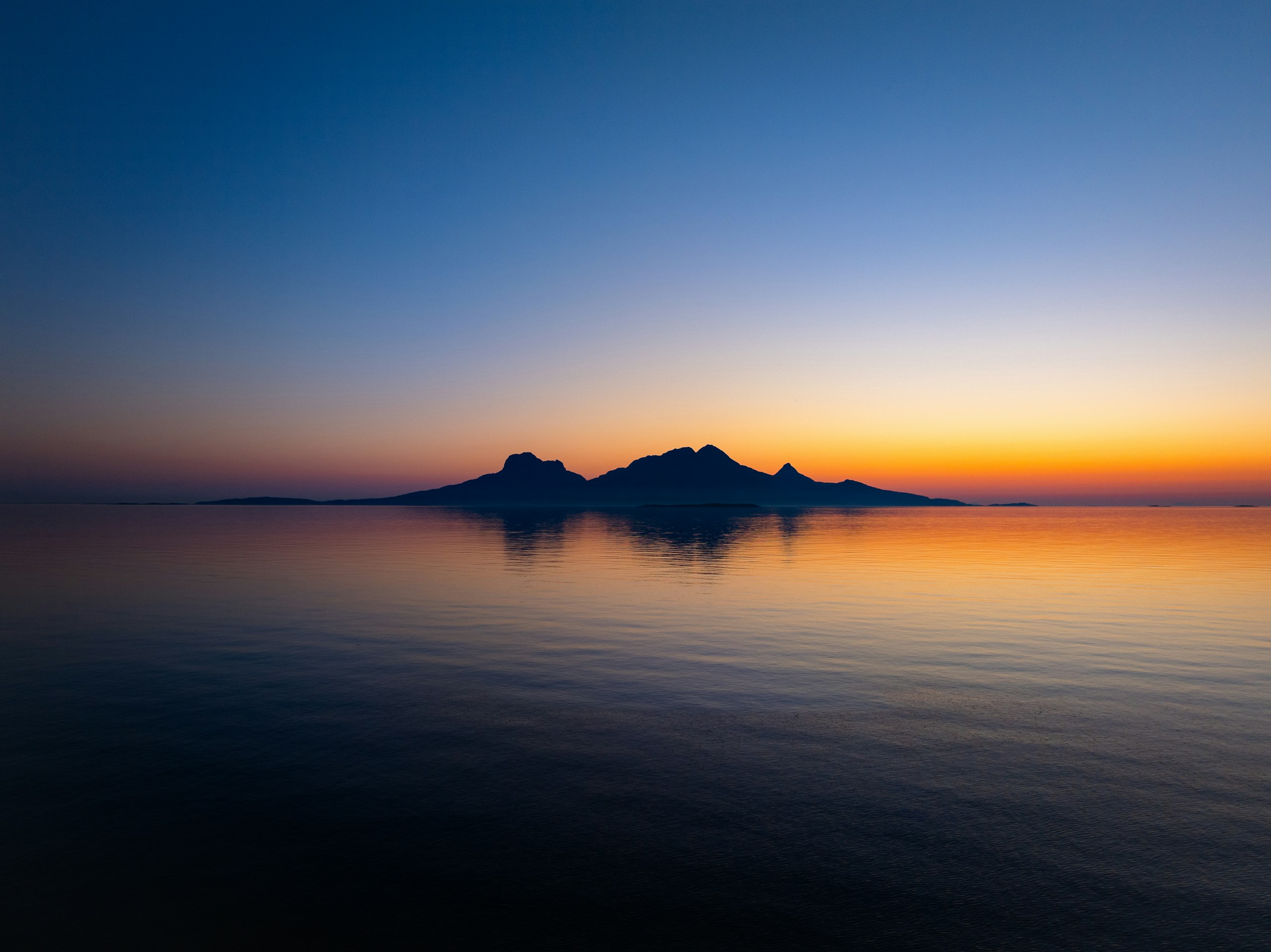 Islands silhouetted against a sunset over the ocean HD Wallpaper
