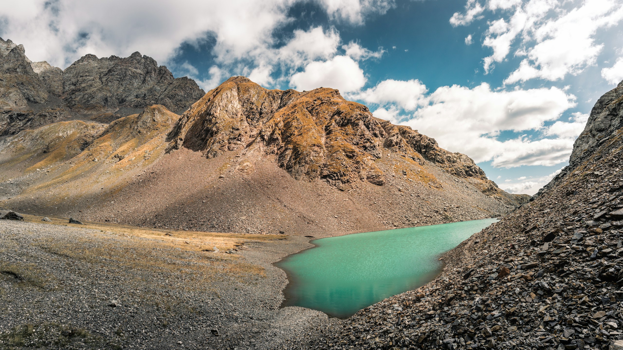 Turquoise lake nestled in a rocky mountain landscape HD Wallpaper