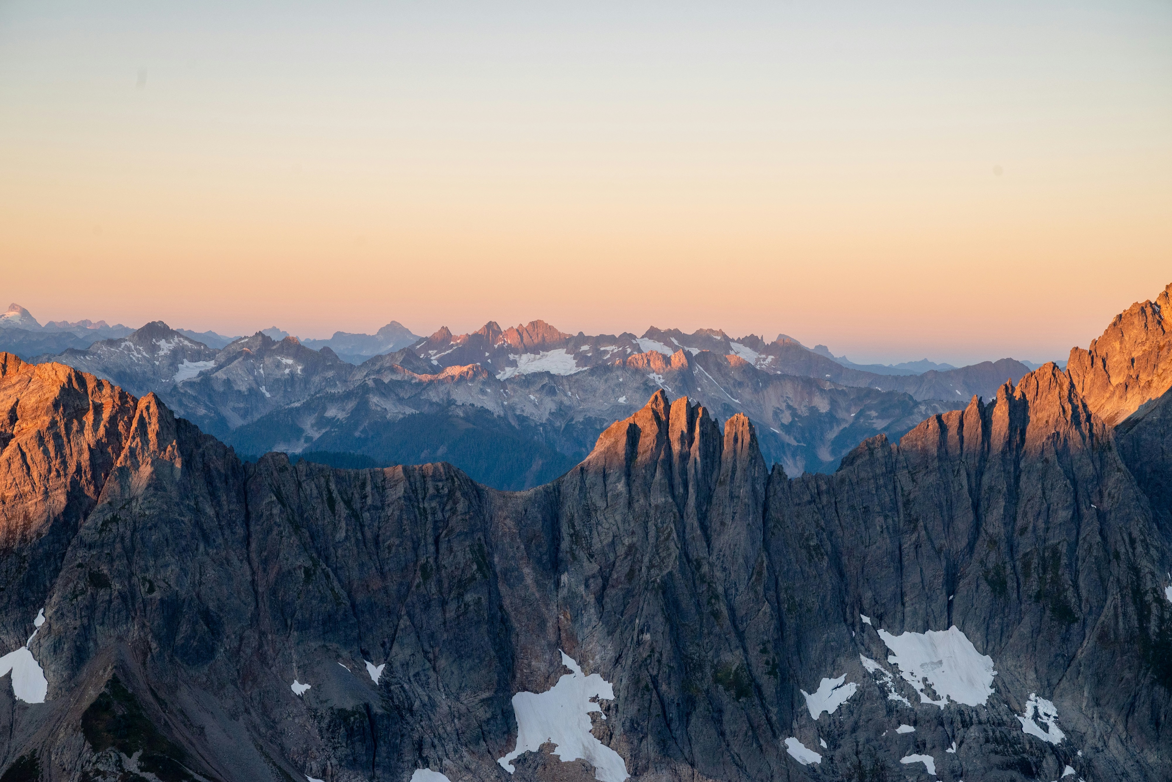 Jagged mountain range at sunrise with snow patches HD Wallpaper