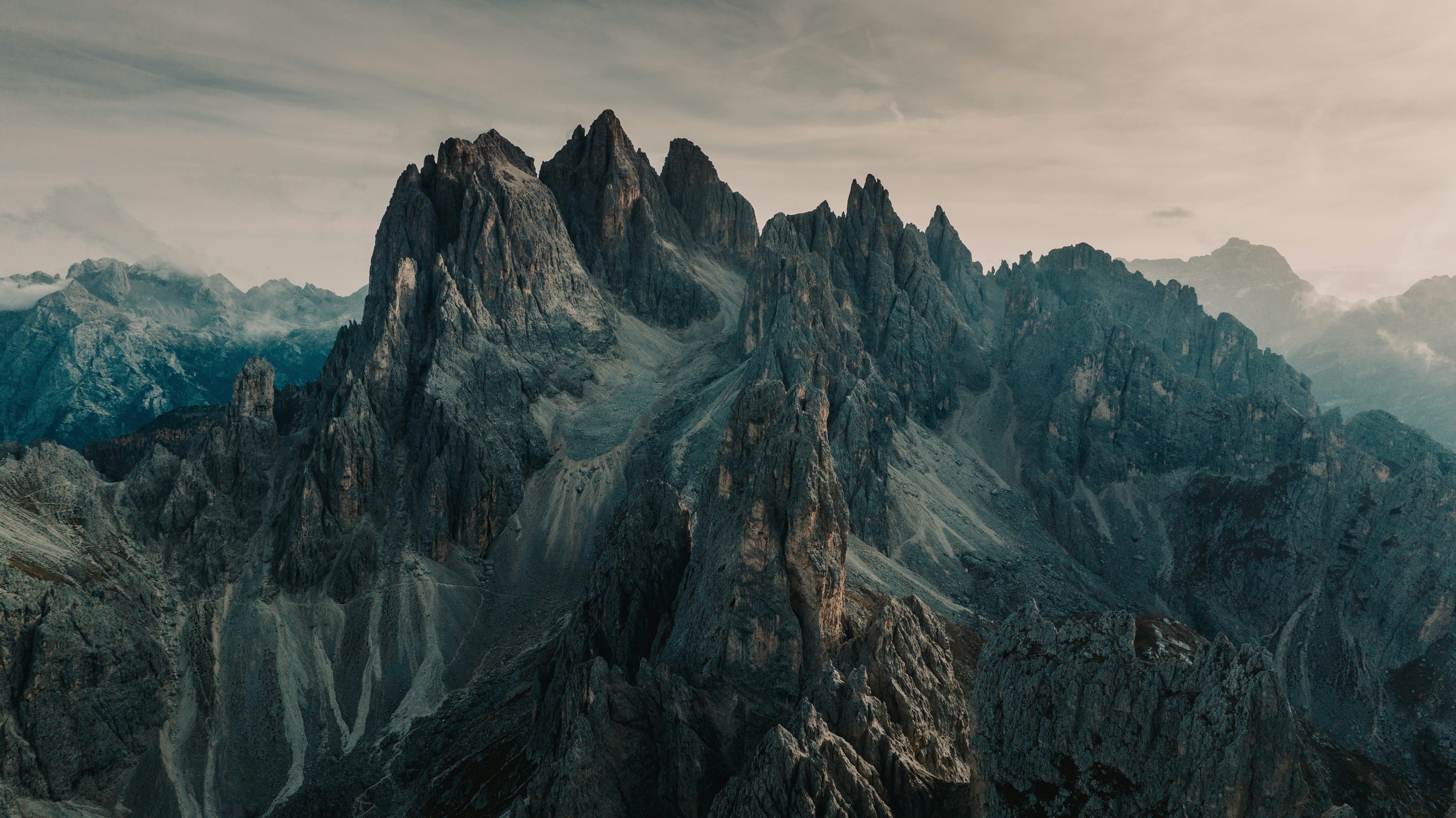 Jagged mountain peaks under a cloudy sky HD Wallpaper