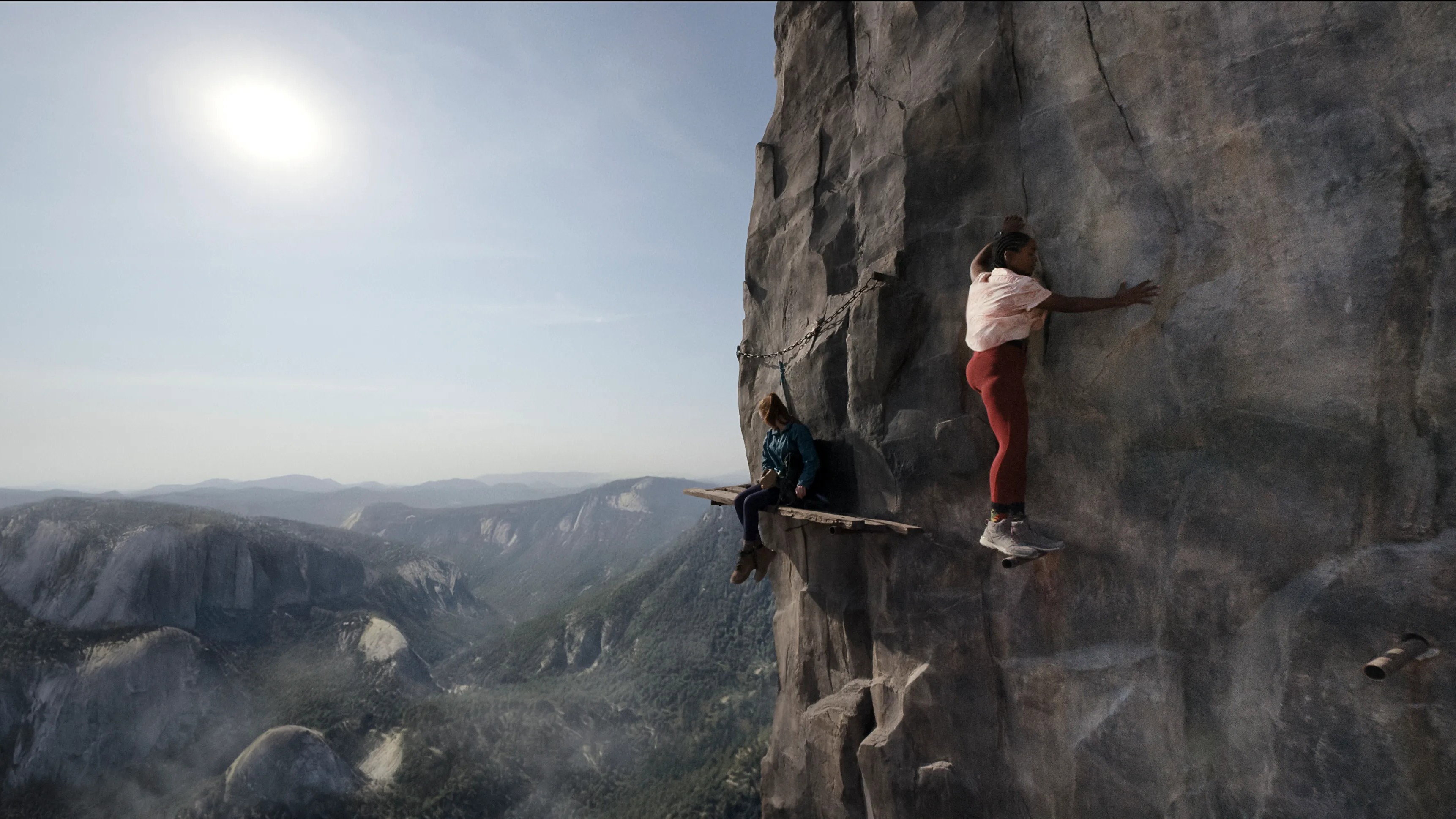Two women climbing a sheer rock face HD Wallpaper