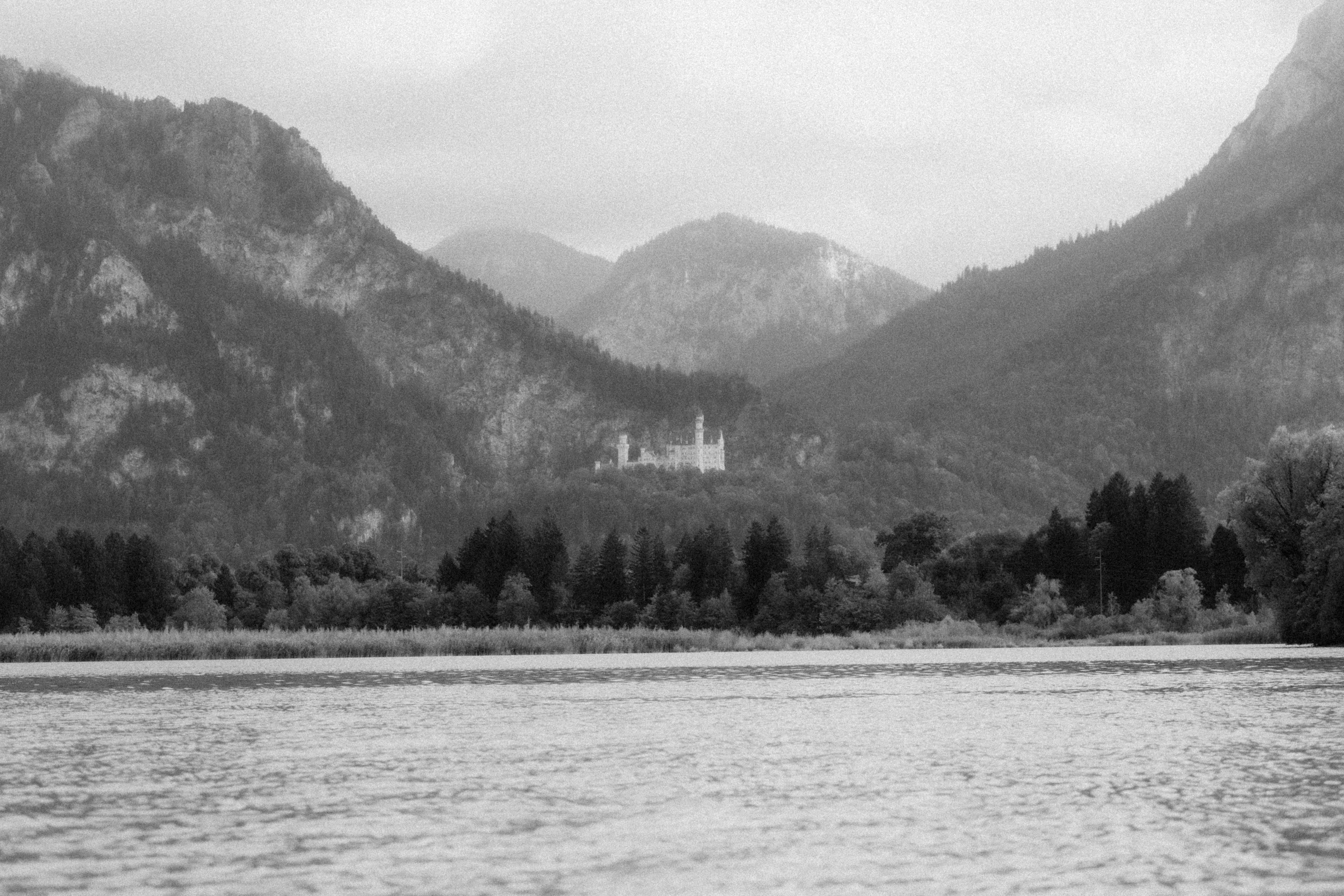 Castle on a hill overlooking a lake and mountains HD Wallpaper