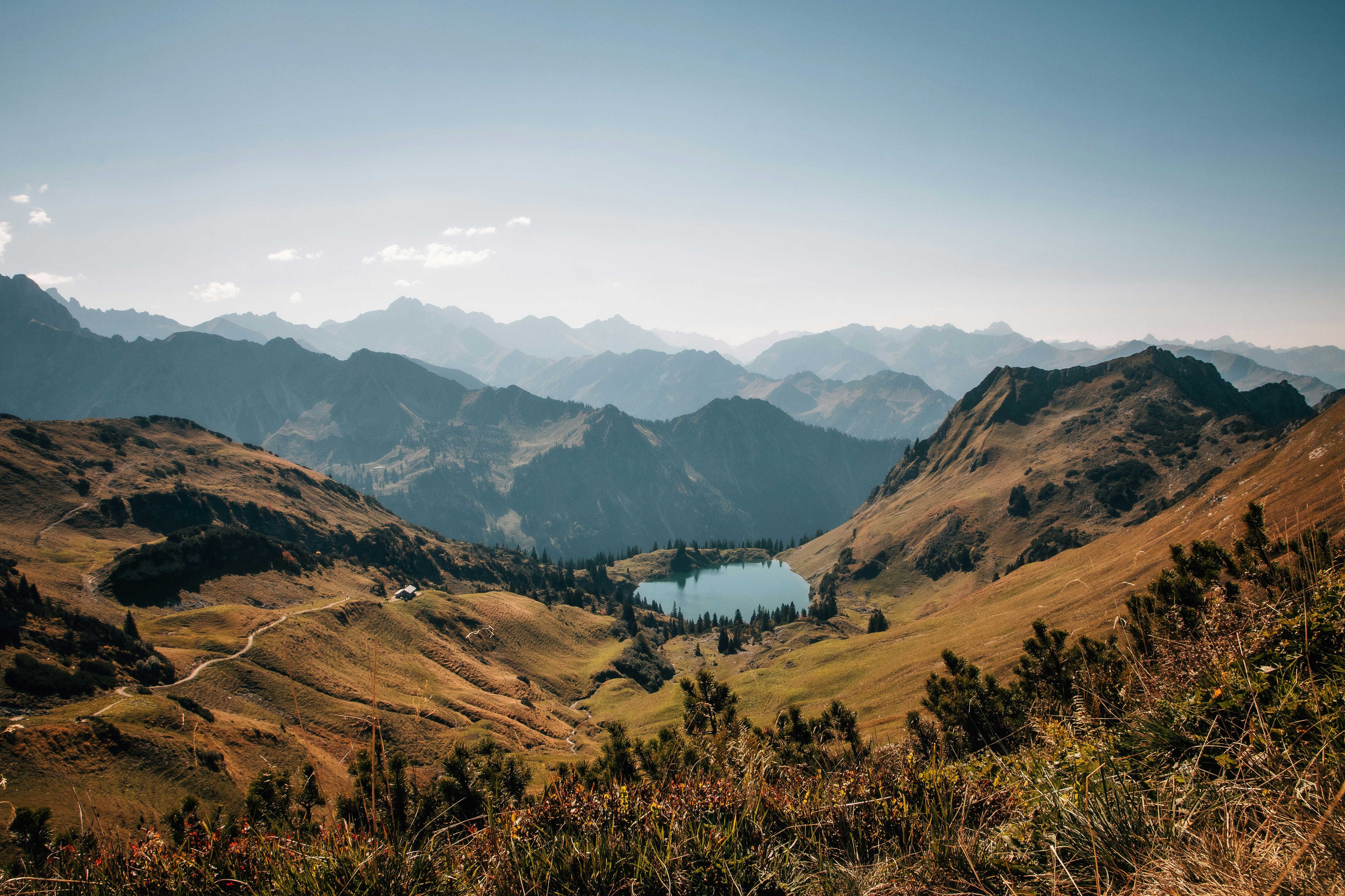 Alpine lake surrounded by mountains and rolling hills HD Wallpaper