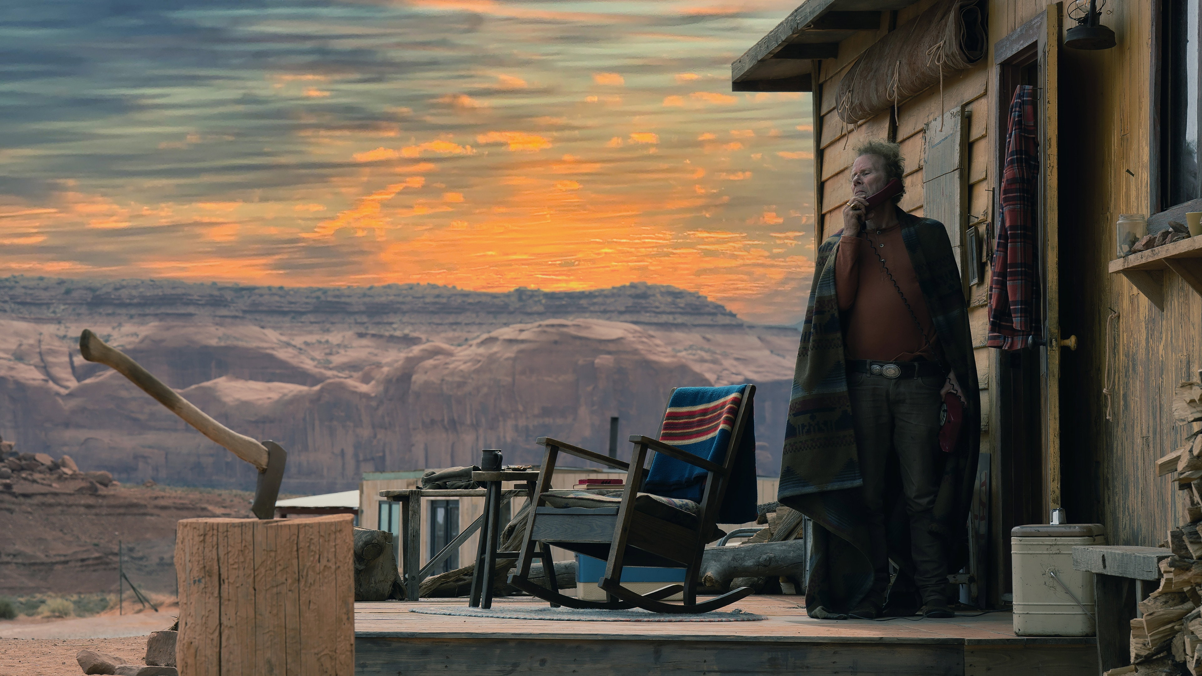 Man on phone in front of cabin with desert landscape HD Wallpaper