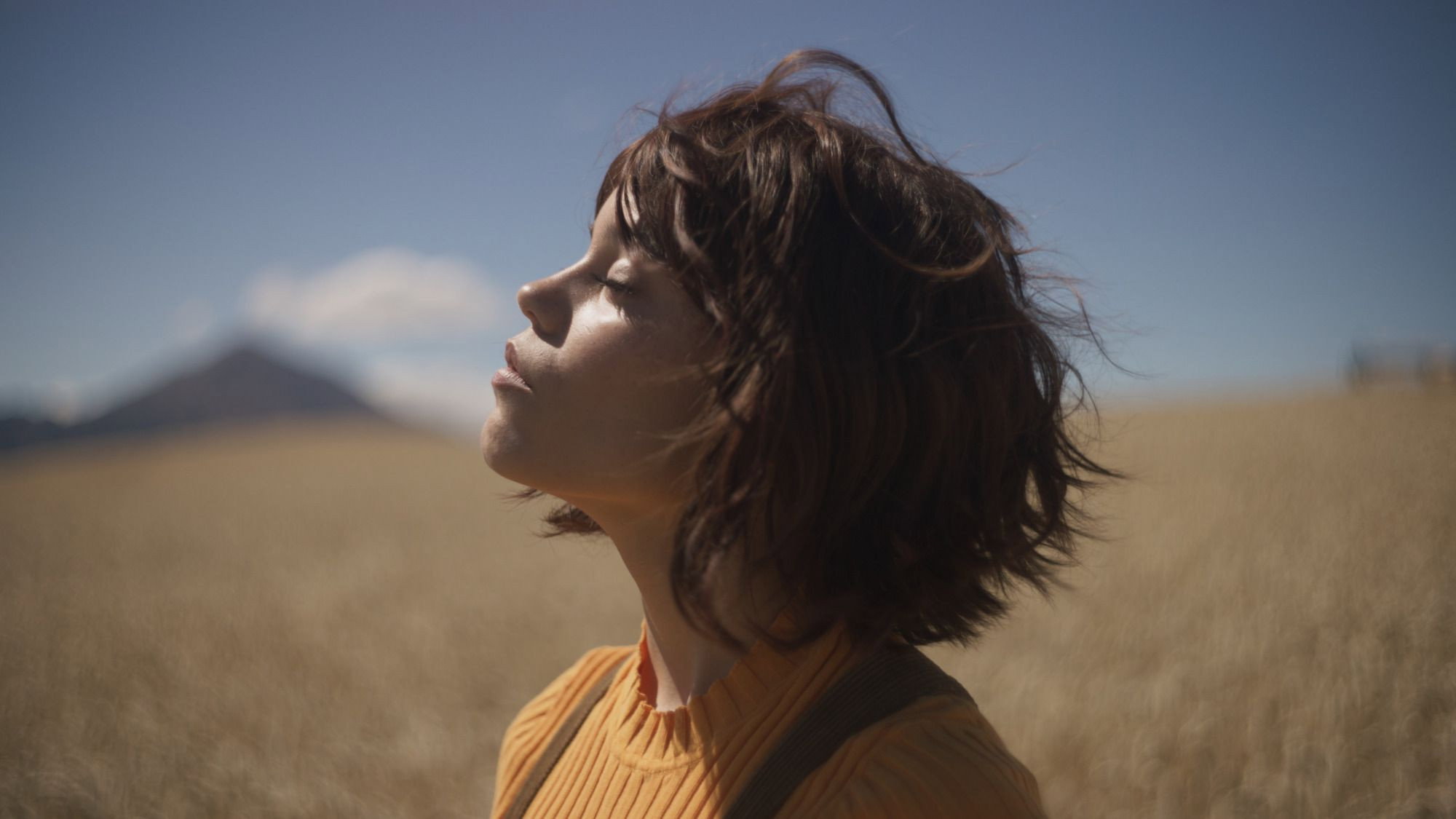 Woman in a field with eyes closed HD Wallpaper