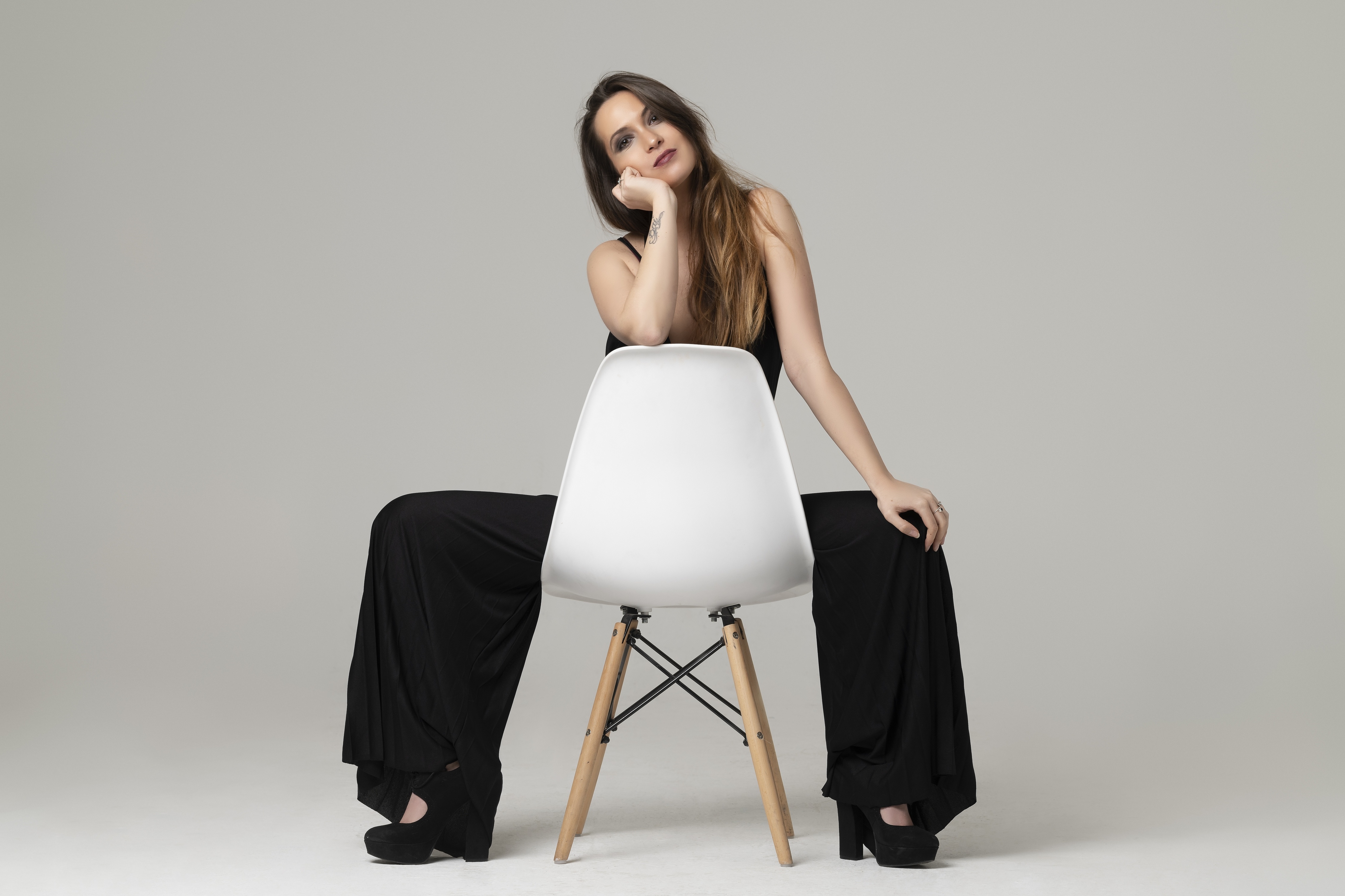 Woman in black jumpsuit sitting on a chair HD Wallpaper
