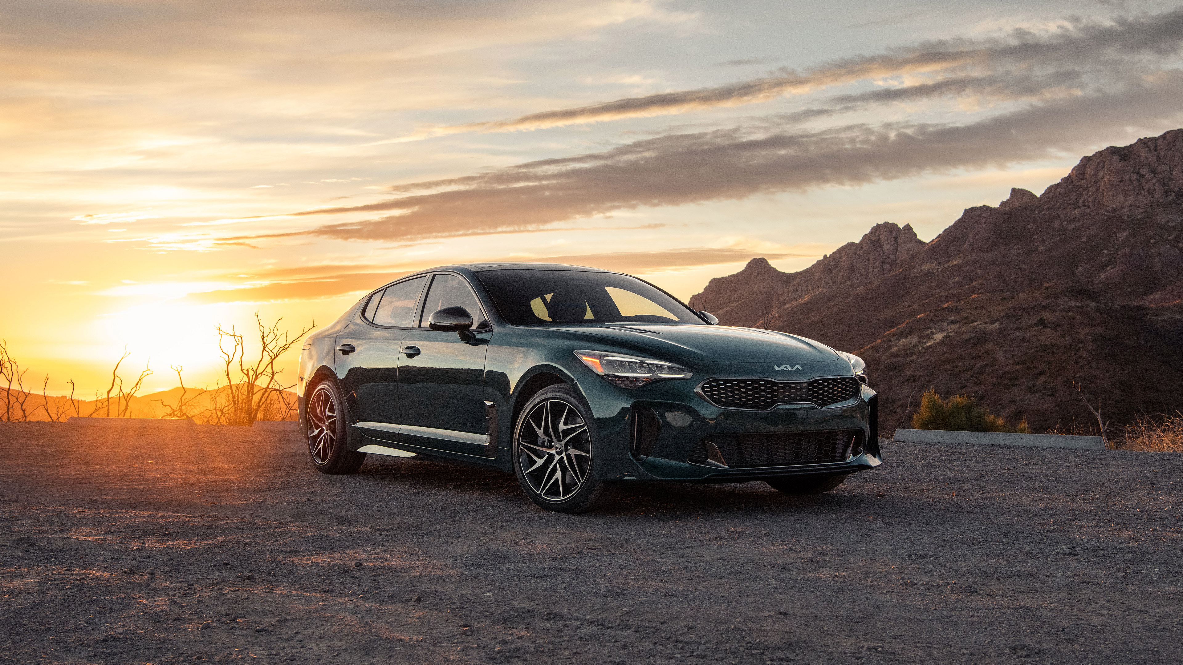 Green Kia Stinger parked at sunset with mountains HD Wallpaper