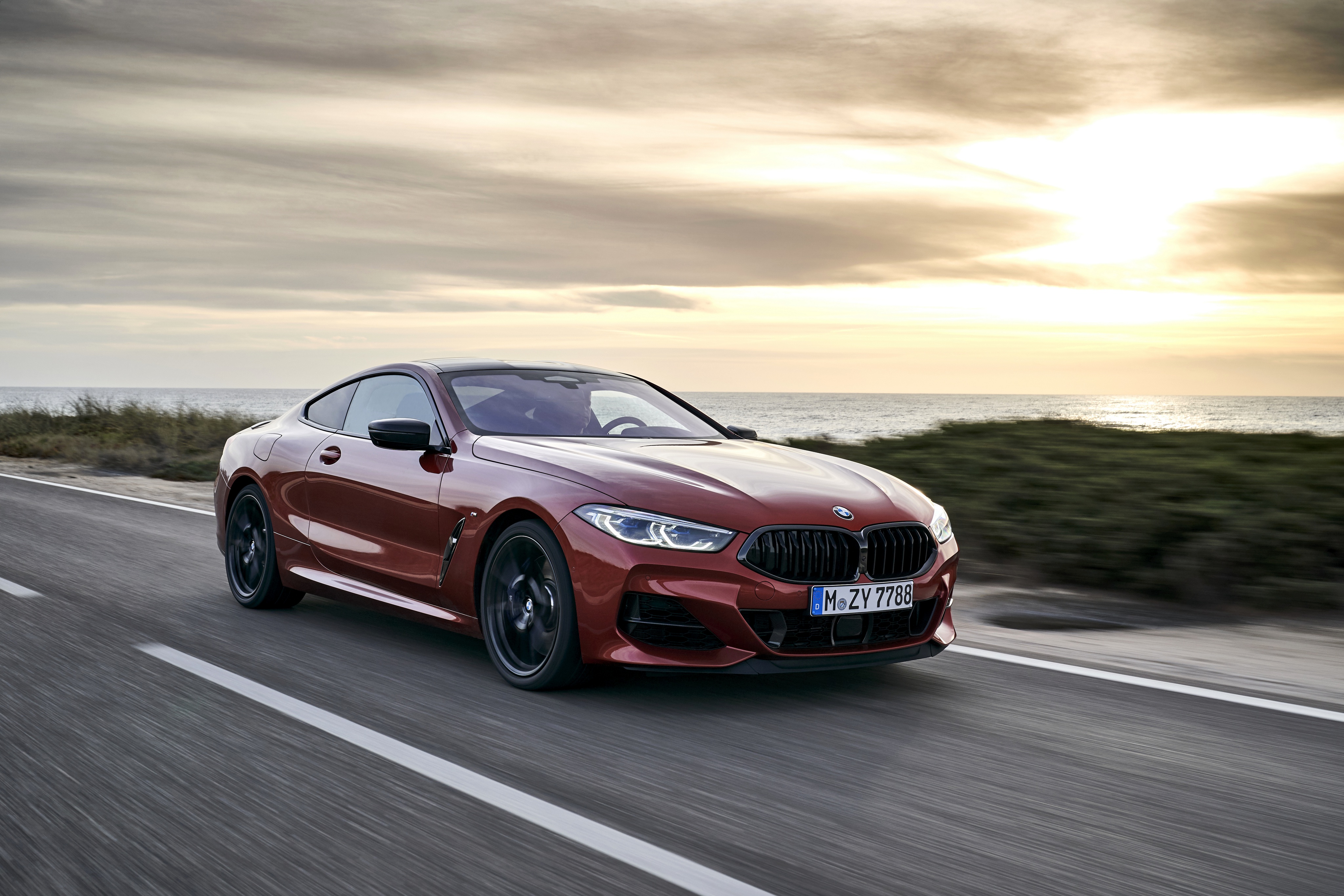 Red BMW 8 Series Coupe driving on coastal road HD Wallpaper