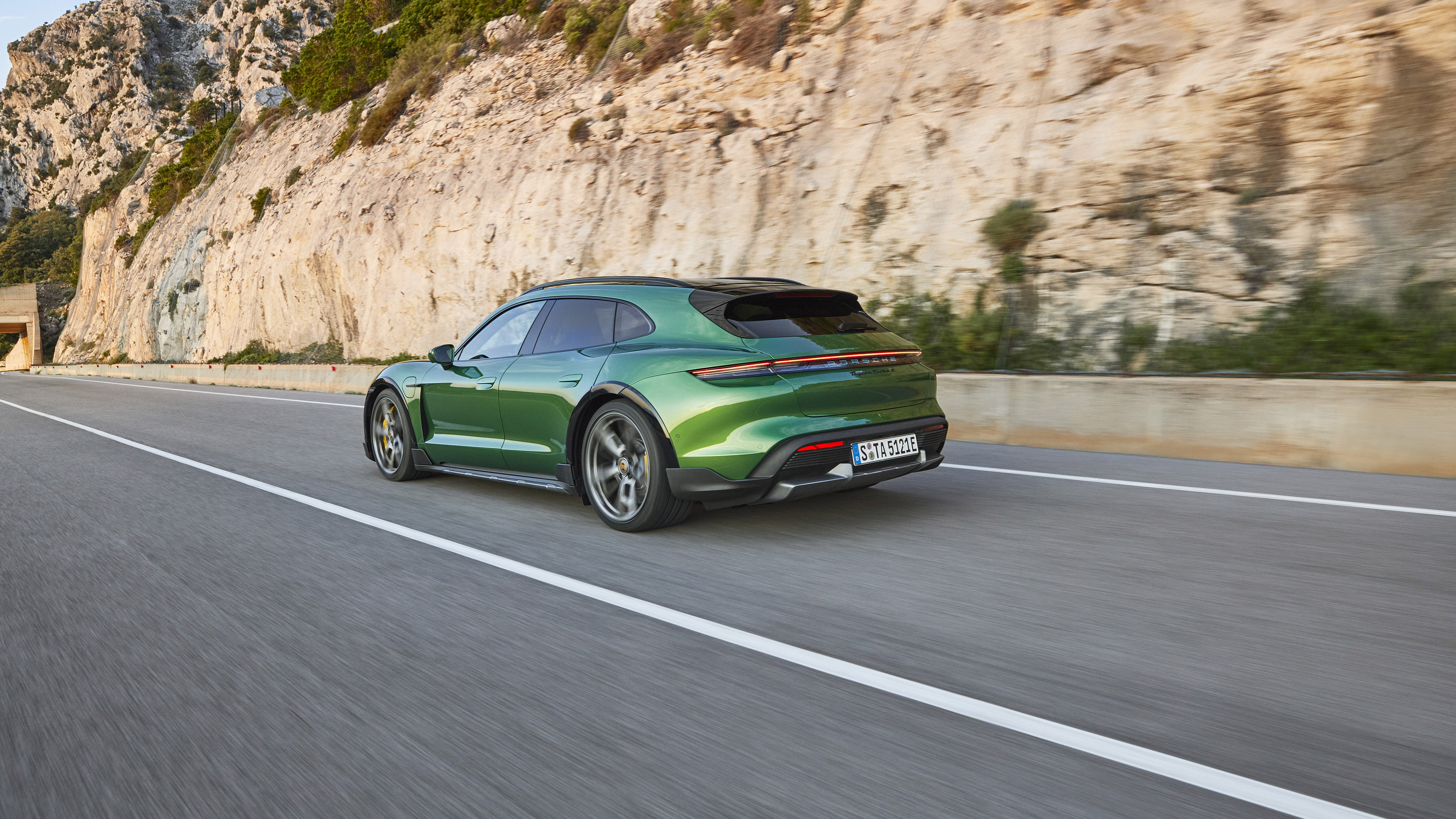 Green Porsche Taycan Turbo S driving on a road HD Wallpaper