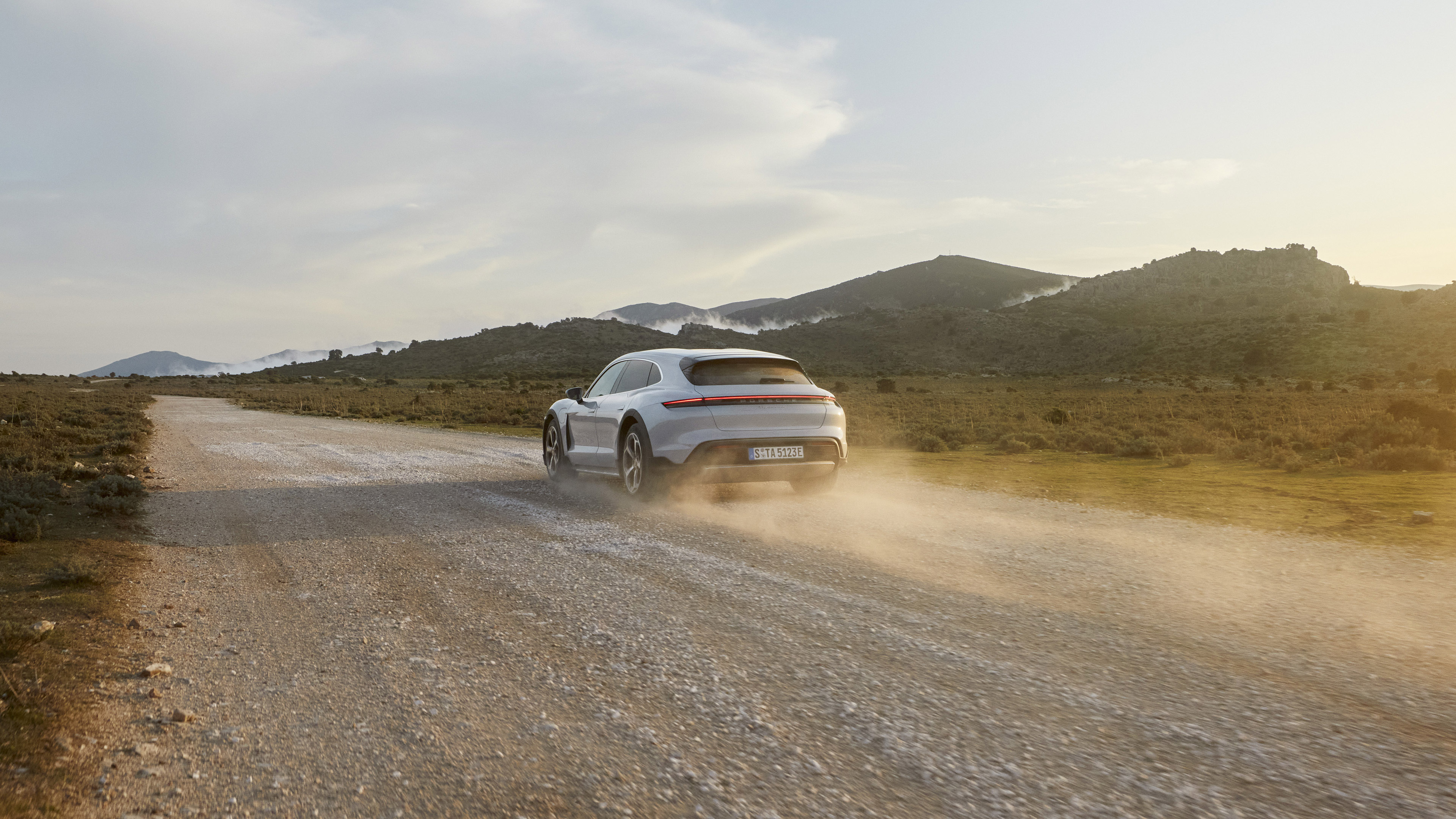 White Porsche Taycan 4S driving on a dirt road HD Wallpaper