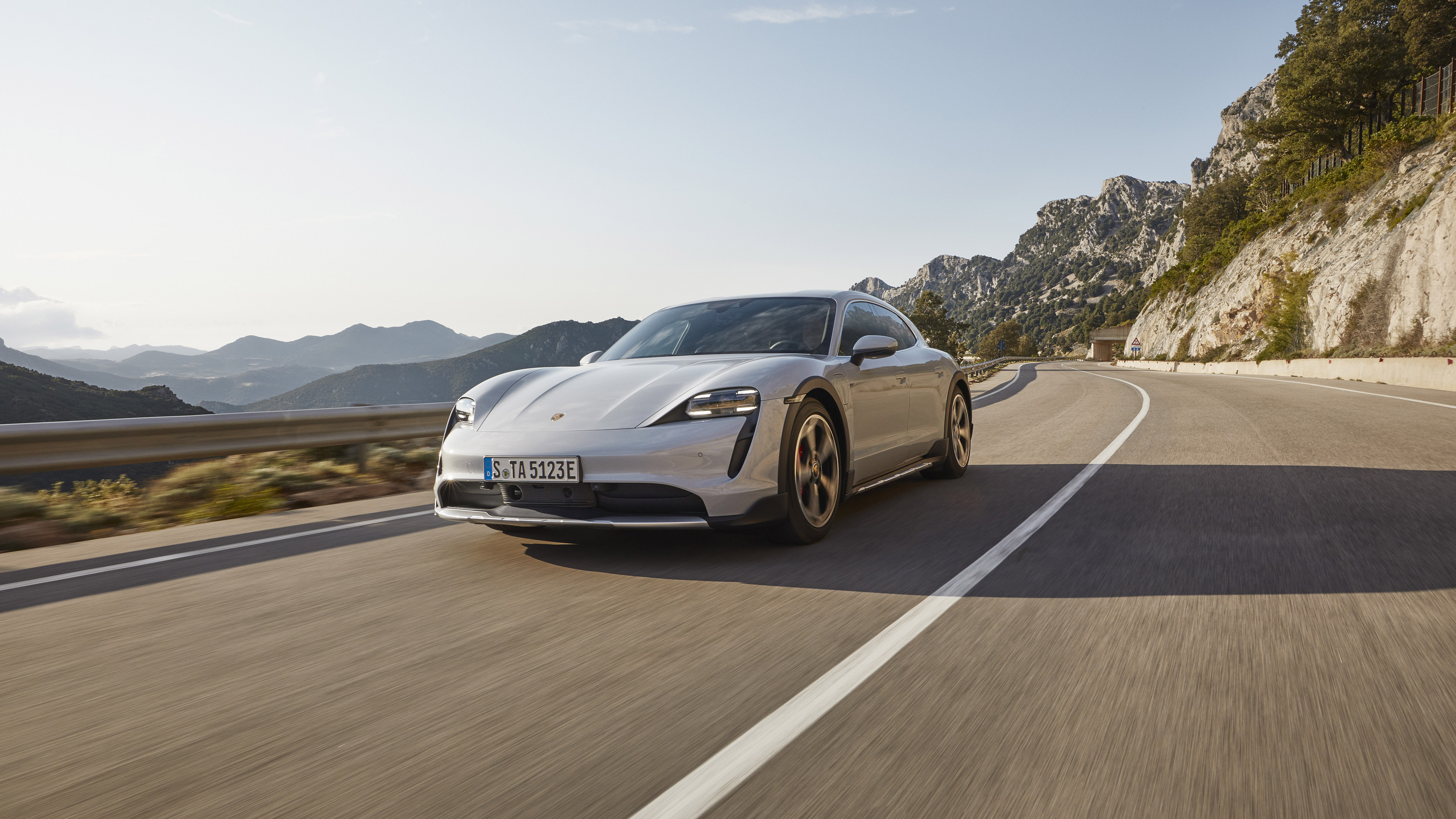 Porsche Taycan 4S driving on a mountain road HD Wallpaper