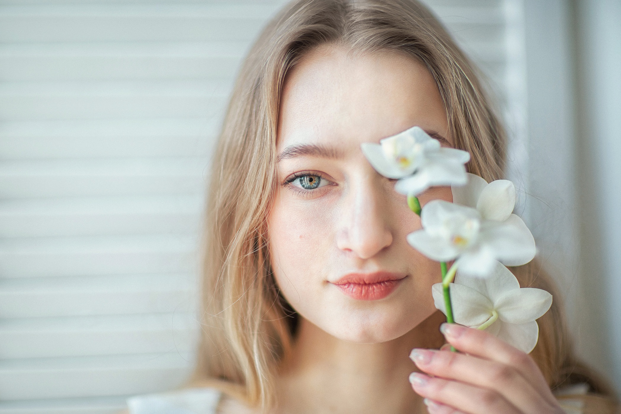 Woman with blonde hair holding white orchids HD Wallpaper