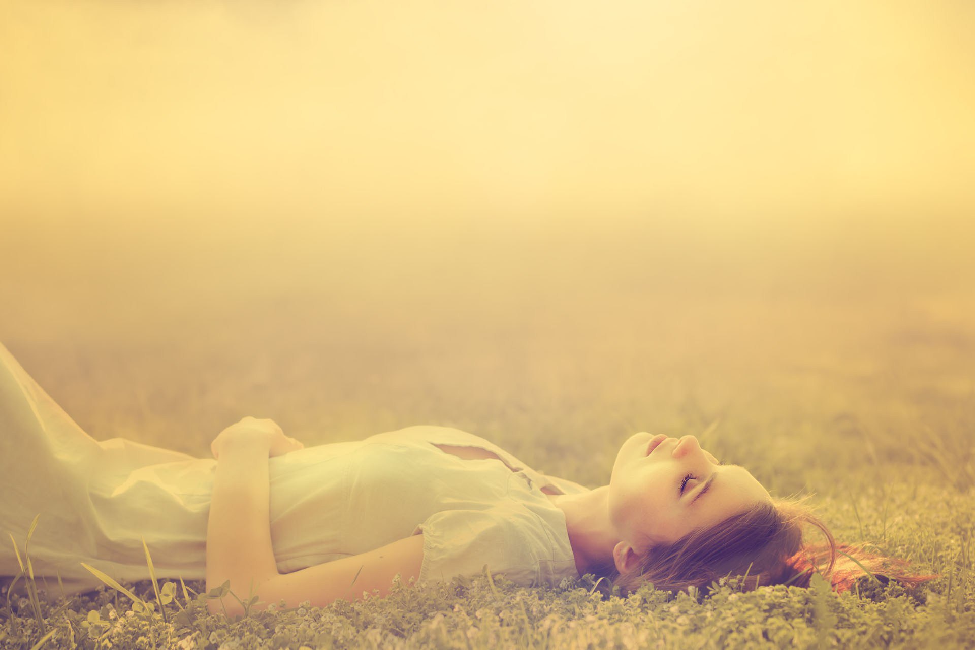 Young woman lying in a grassy field HD Wallpaper