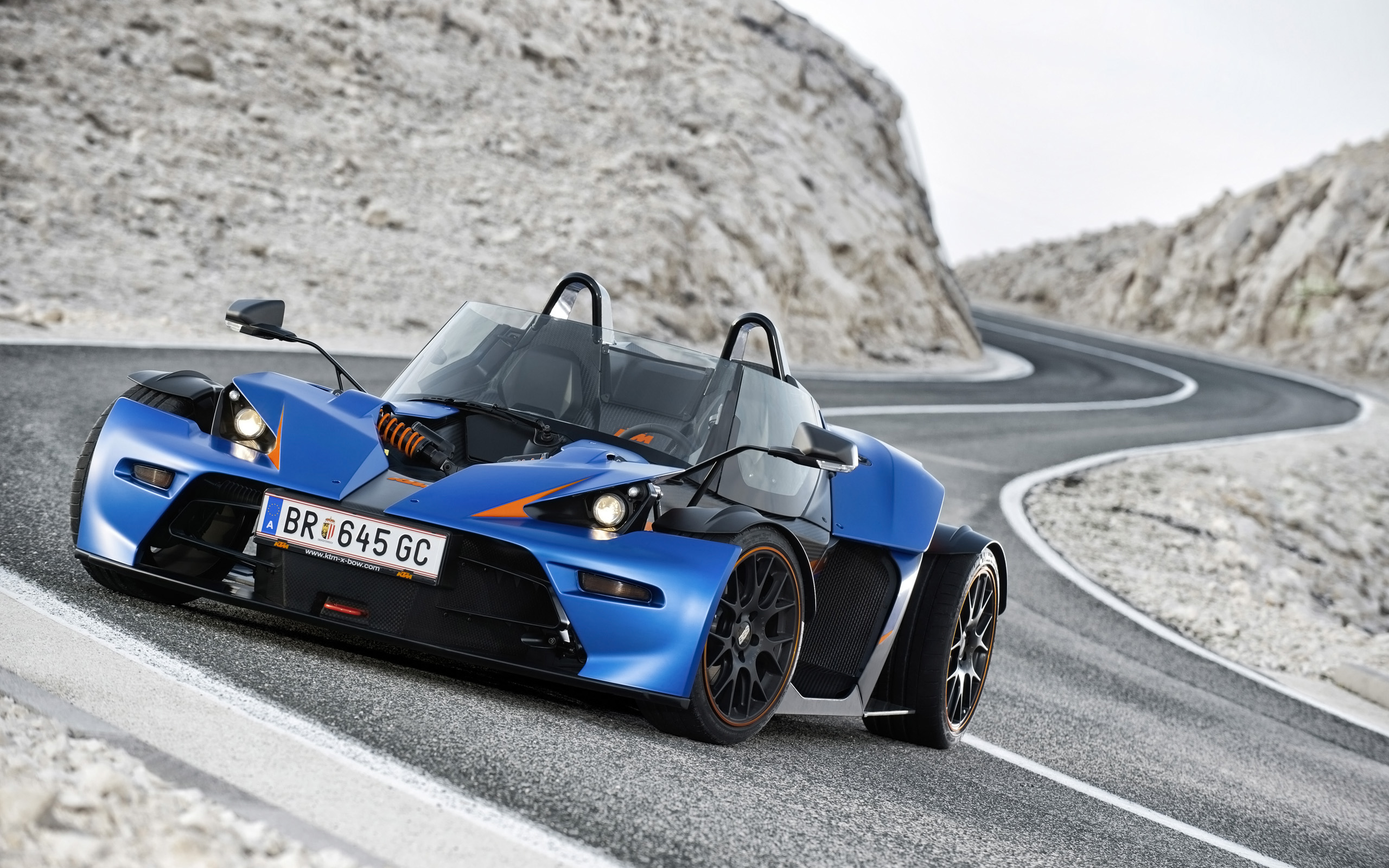 Blue KTM X-Bow GT driving on a winding road HD Wallpaper