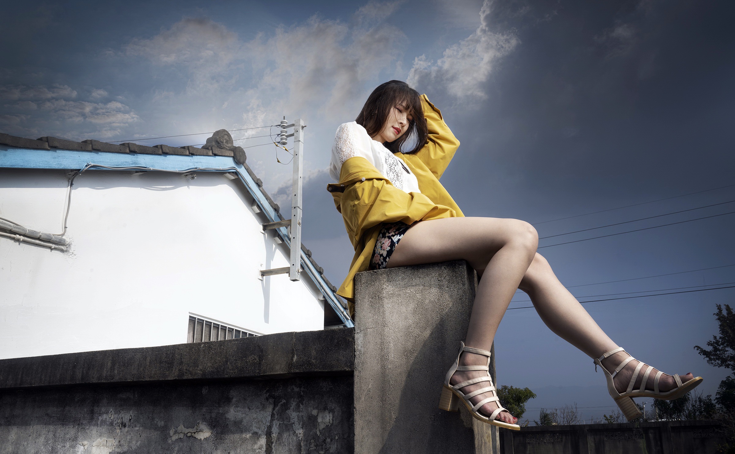 Young Asian woman in yellow jacket sitting on wall HD Wallpaper