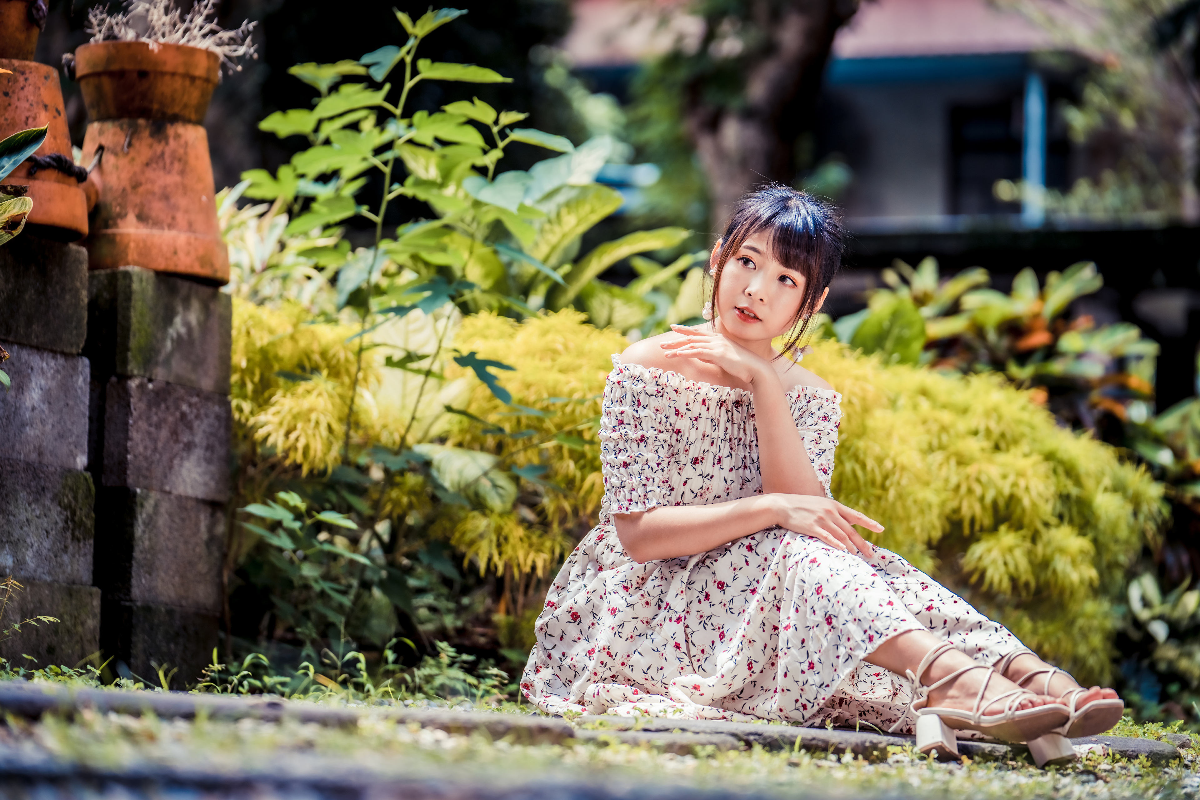 Asian woman in floral dress sitting in garden HD Wallpaper