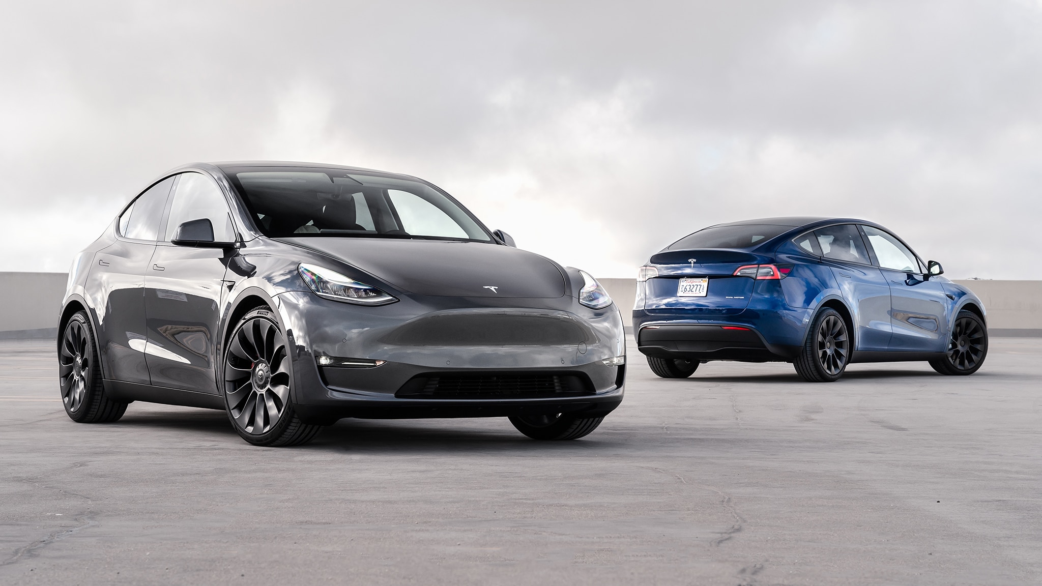 Two Tesla Model Y cars on a concrete surface HD Wallpaper