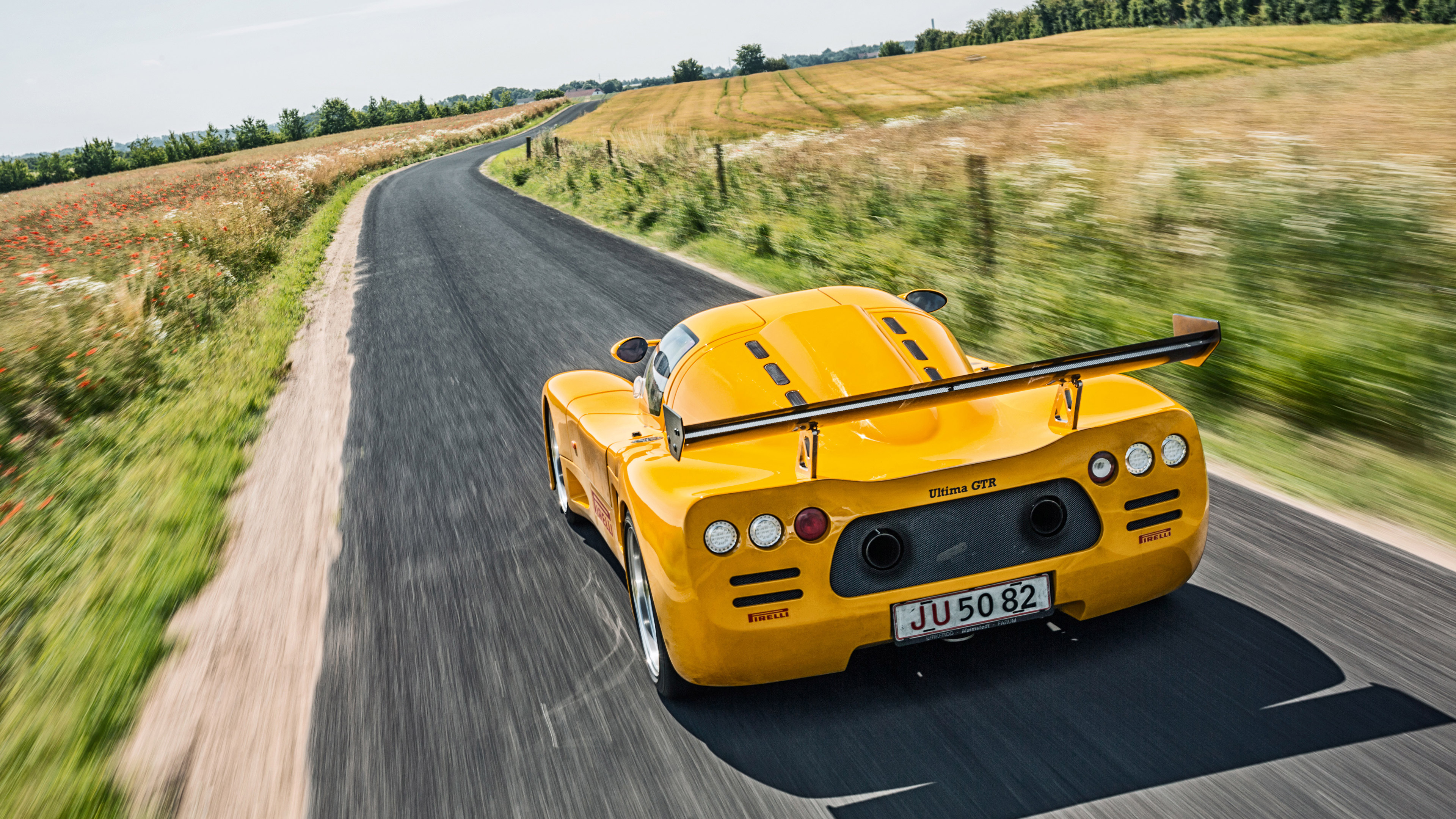 Yellow Ultima GTR driving on a country road HD Wallpaper