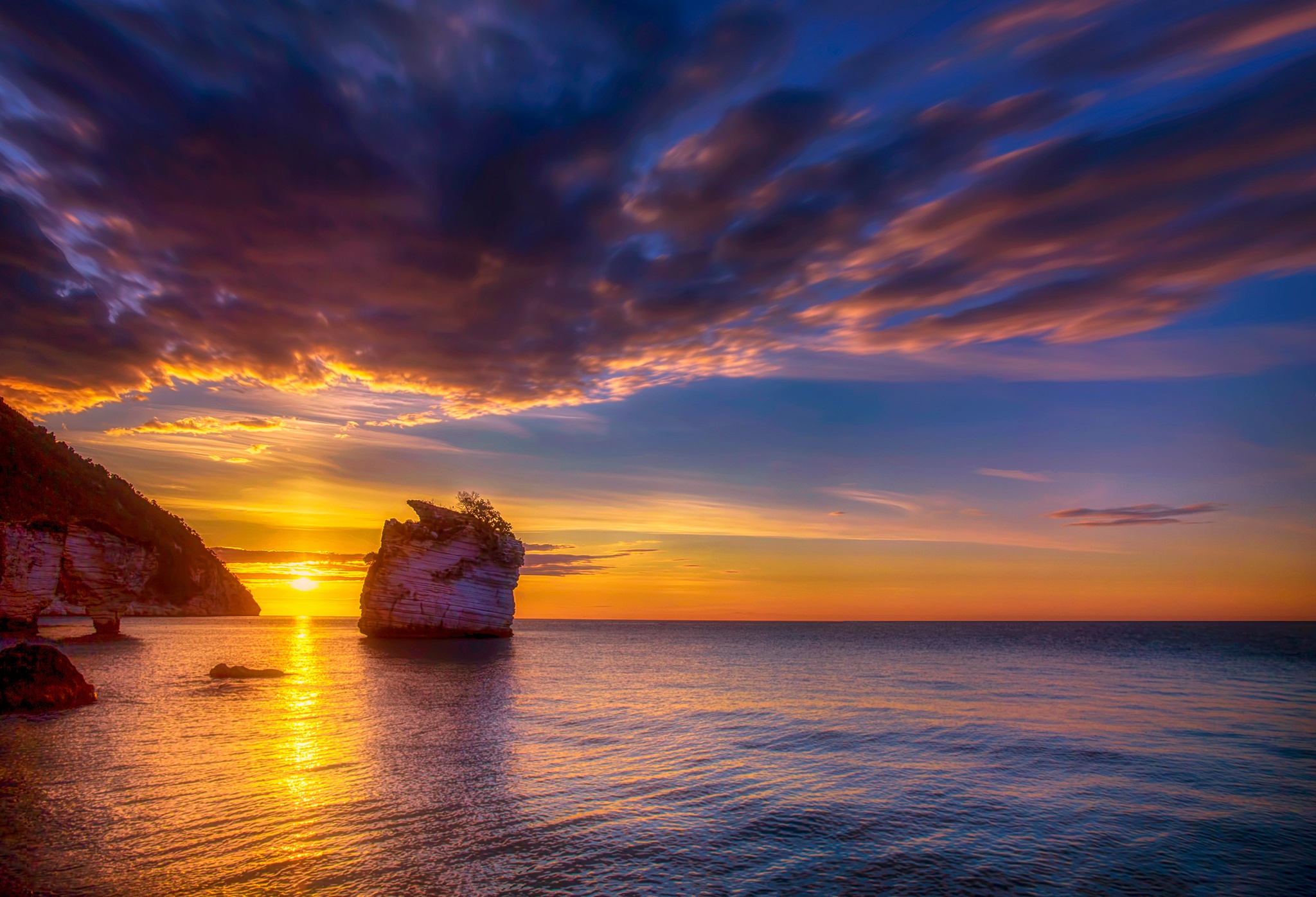 Sunrise over the ocean with rock formations on the coast HD Wallpaper