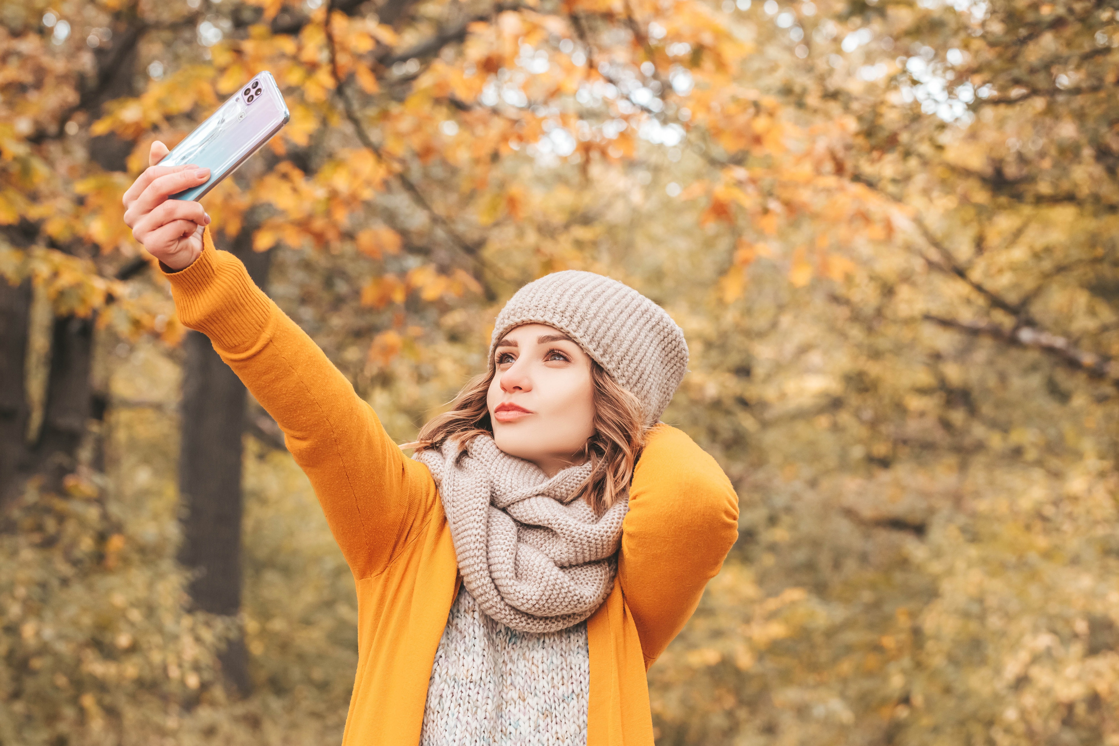 Woman taking a selfie with a smartphone in autumn park HD Wallpaper