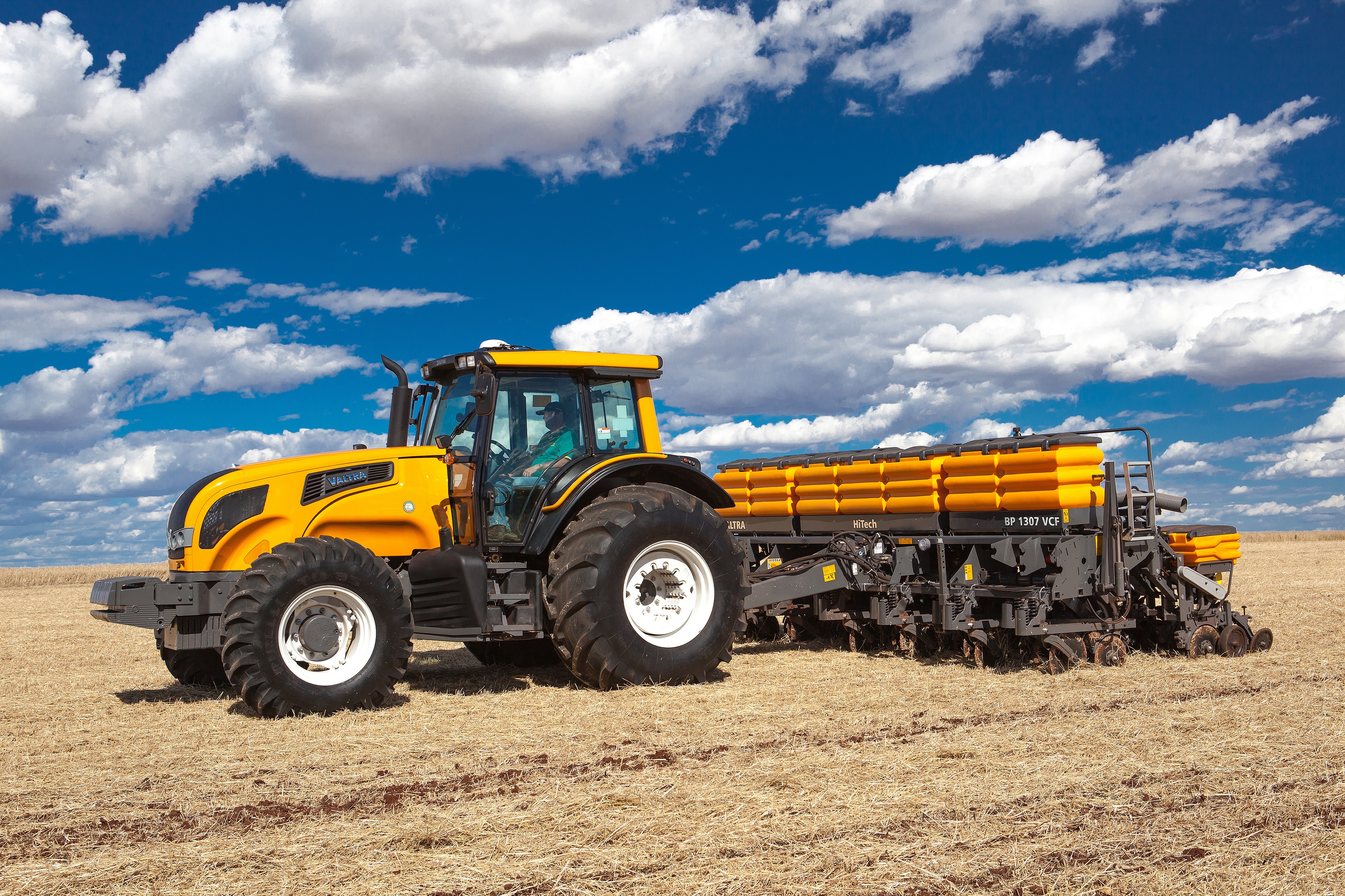 Yellow Valtra tractor with planter in a field HD Wallpaper
