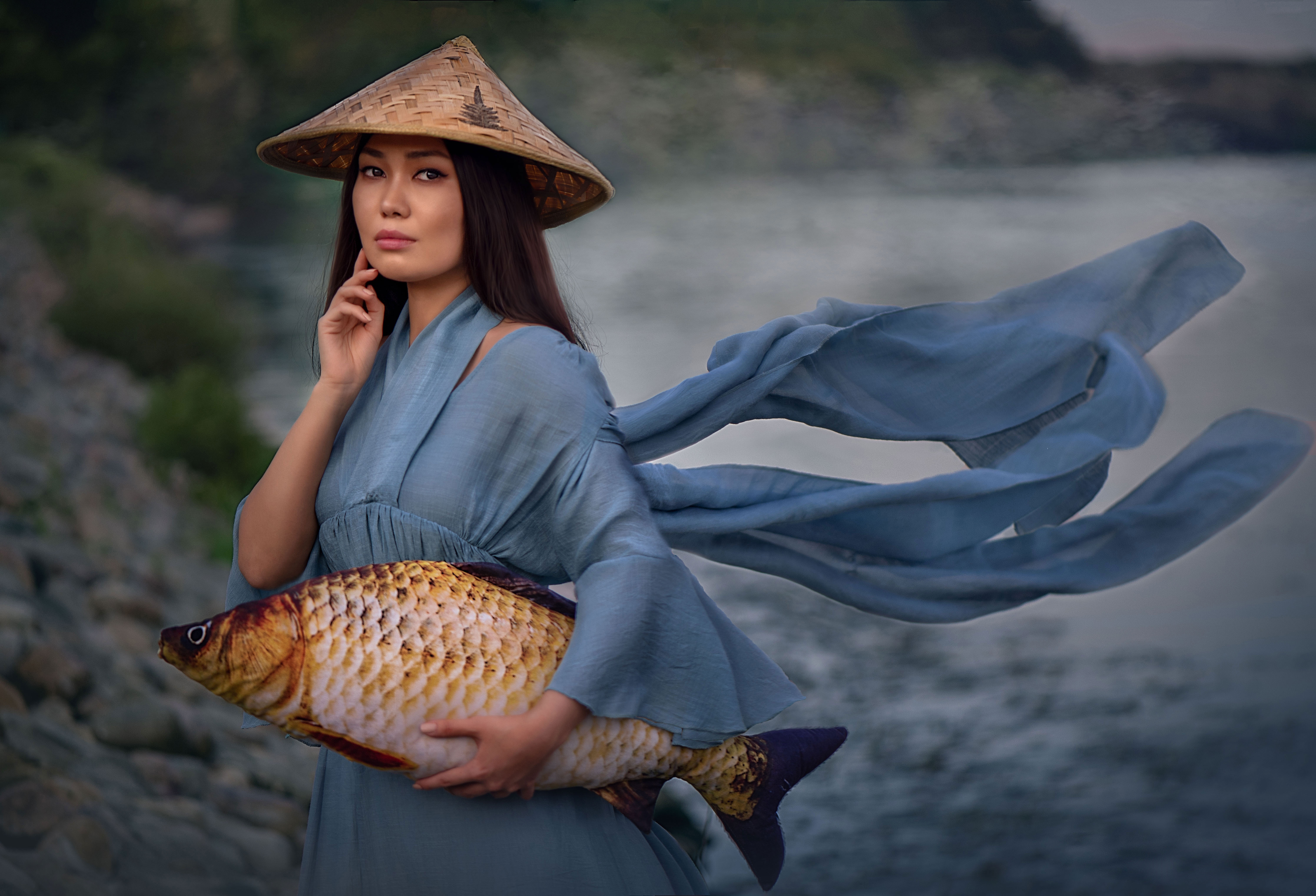 Woman in conical hat holding a large fish by the water HD Wallpaper