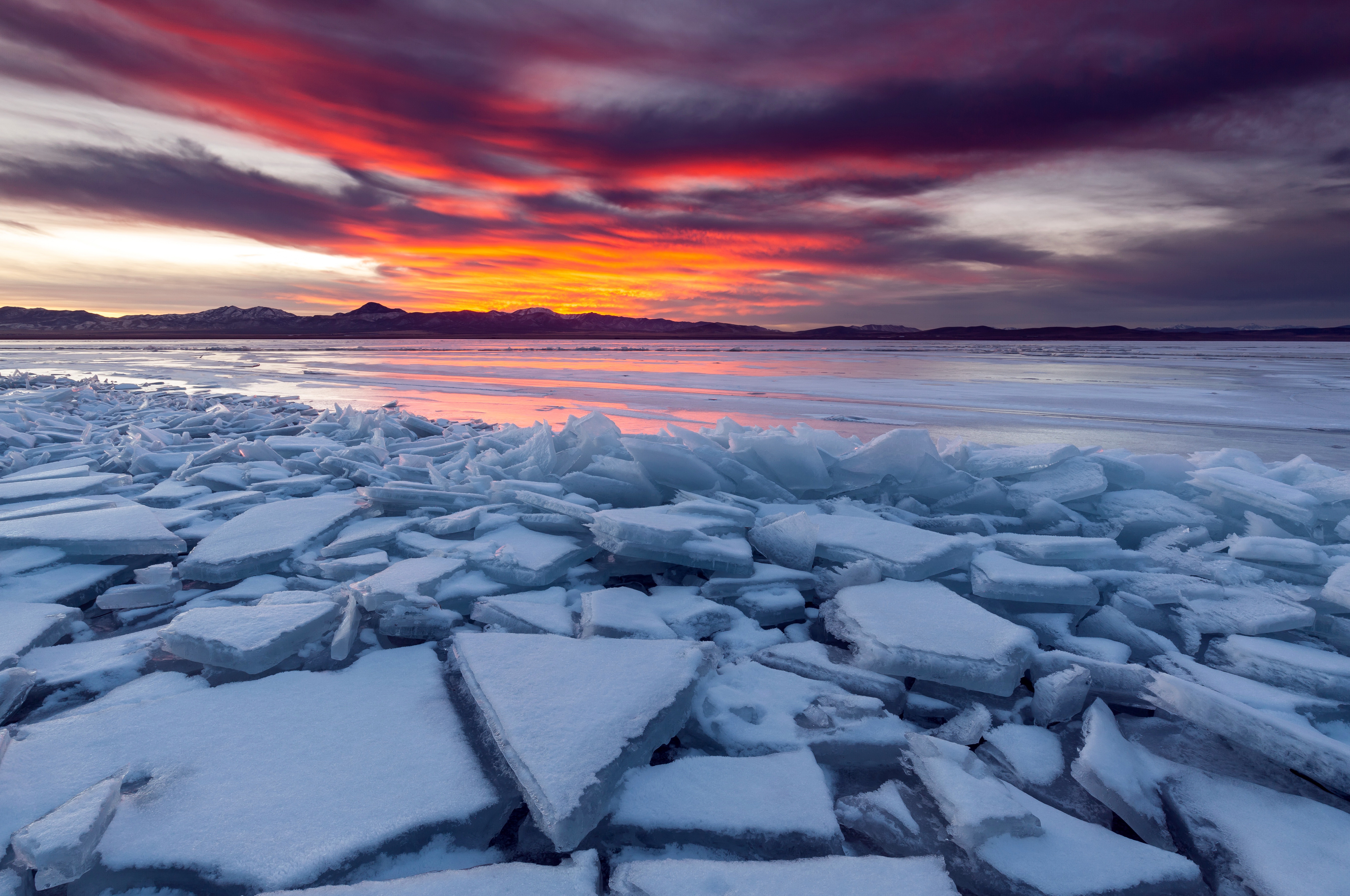 Broken ice on a frozen lake at sunset HD Wallpaper