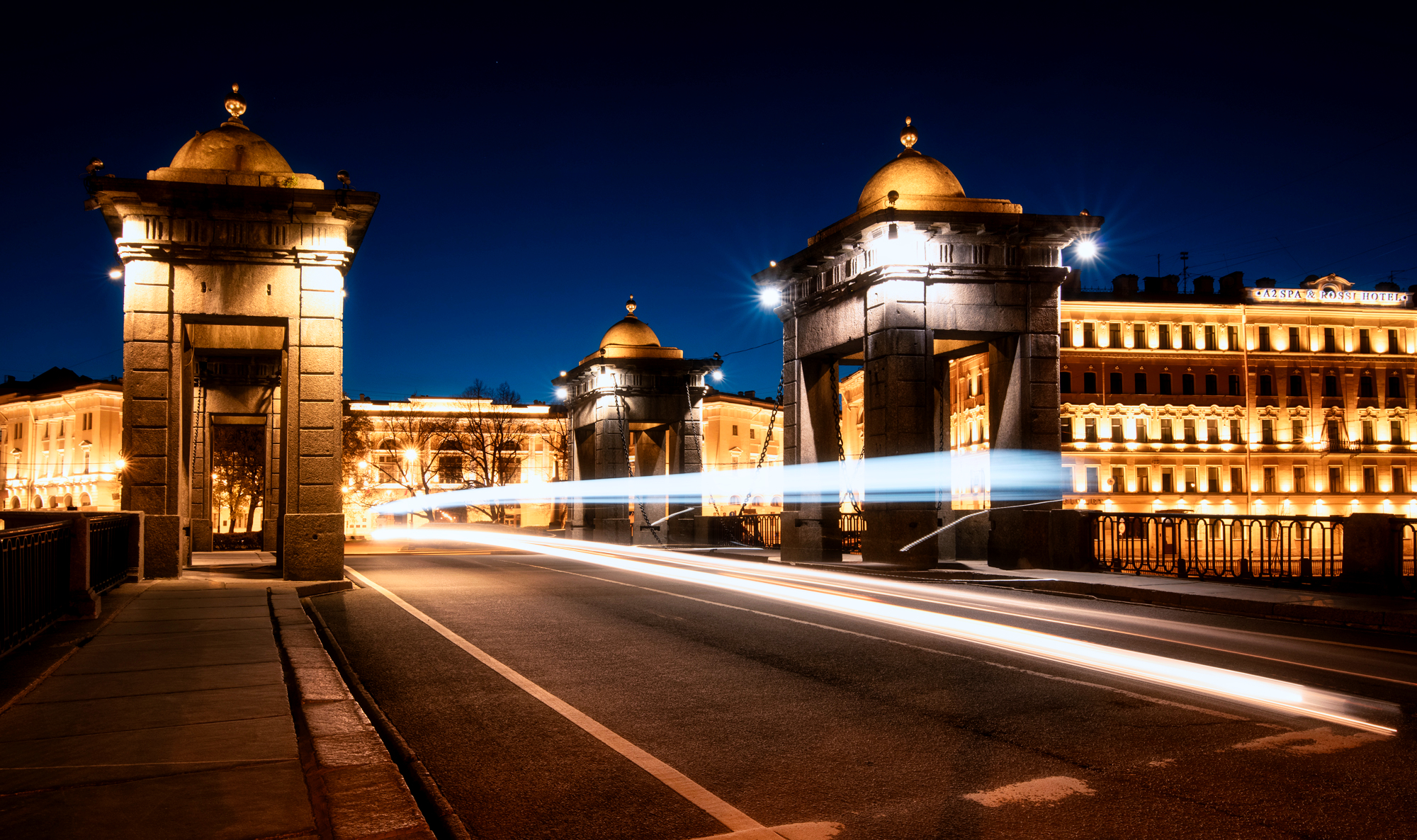Nighttime bridge with light trails and illuminated buildings HD Wallpaper
