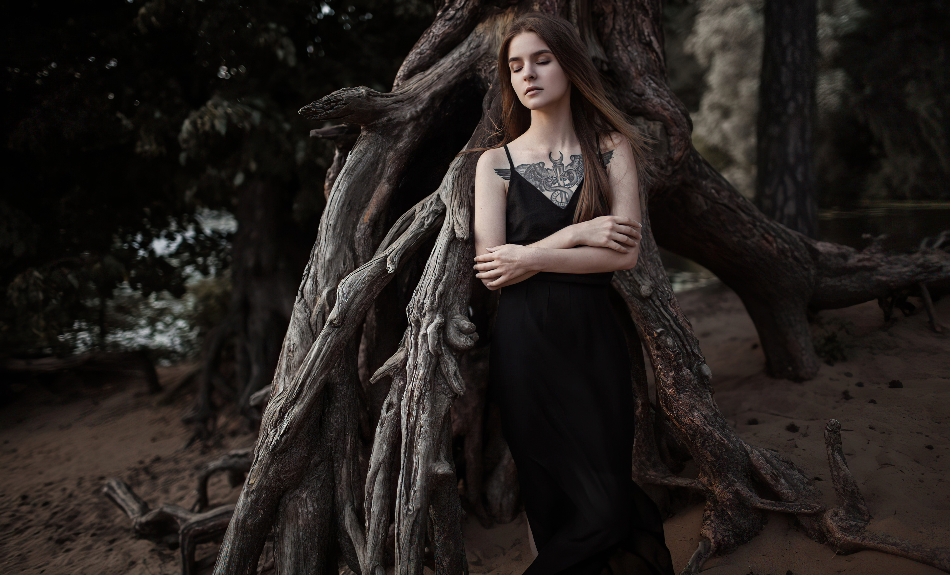 Woman with tattoo in black dress near tree roots HD Wallpaper
