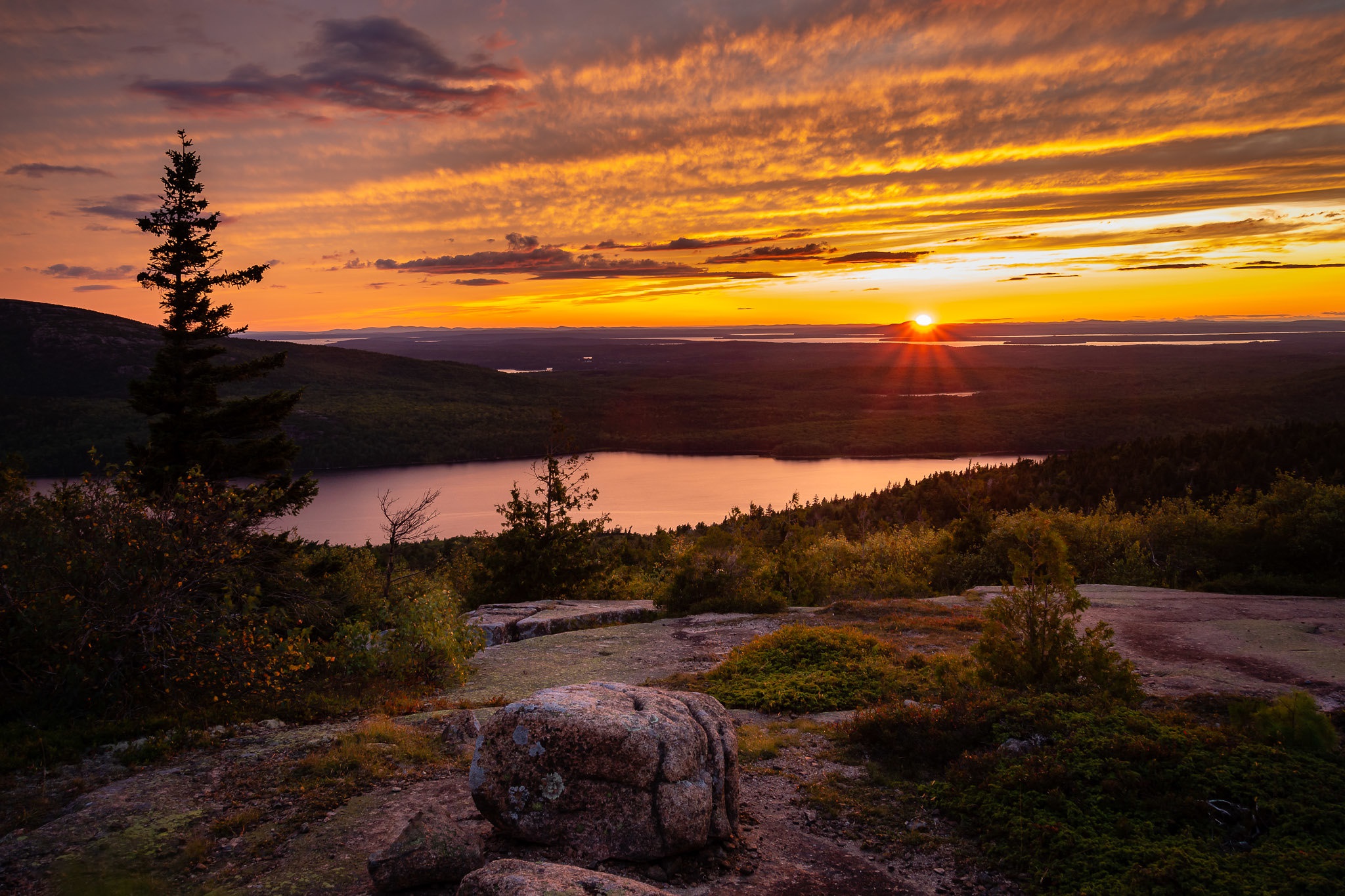 Sunset over a lake and forest from a rocky viewpoint HD Wallpaper
