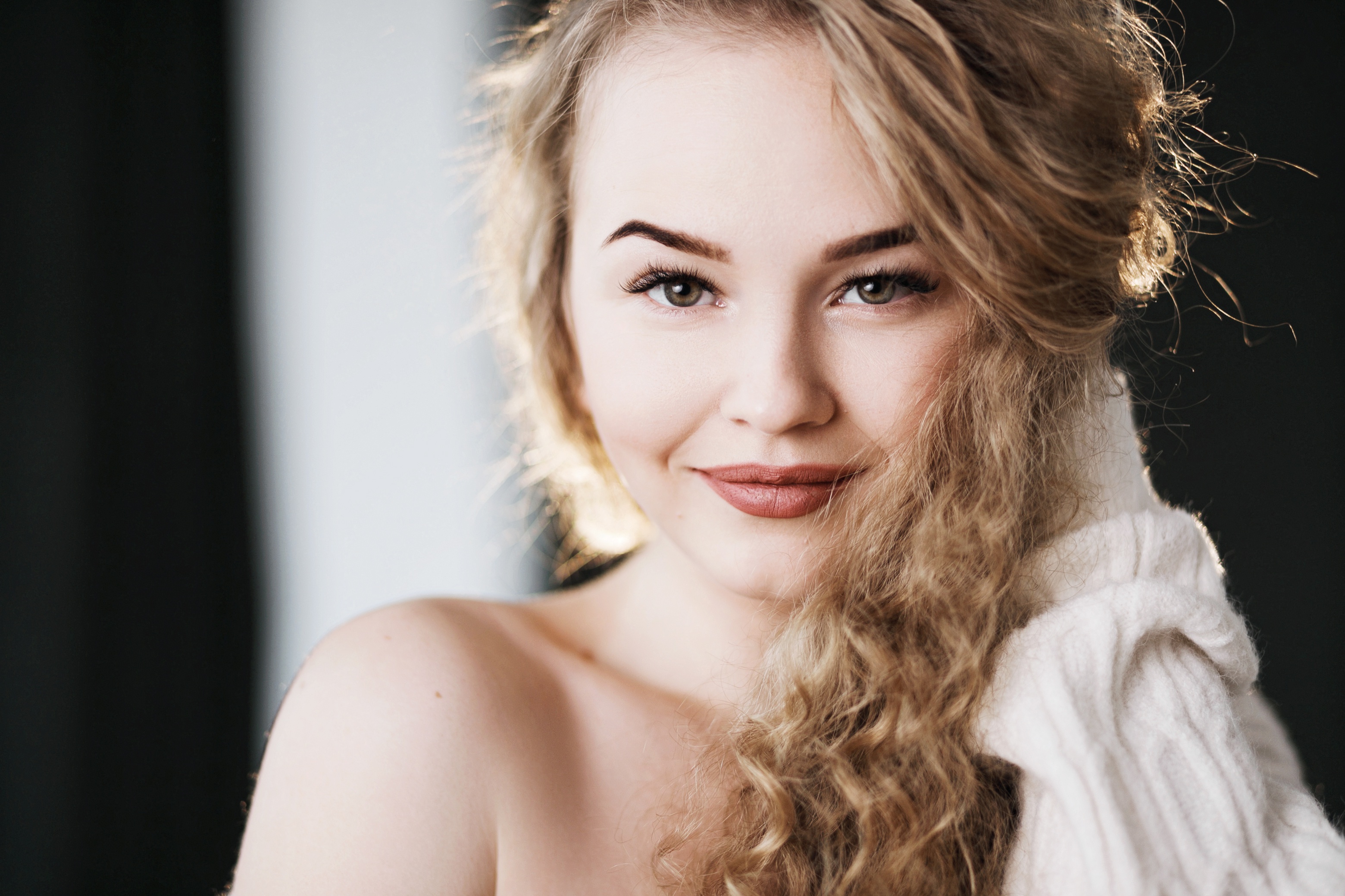 Woman with blonde curly hair wearing a white sweater HD Wallpaper