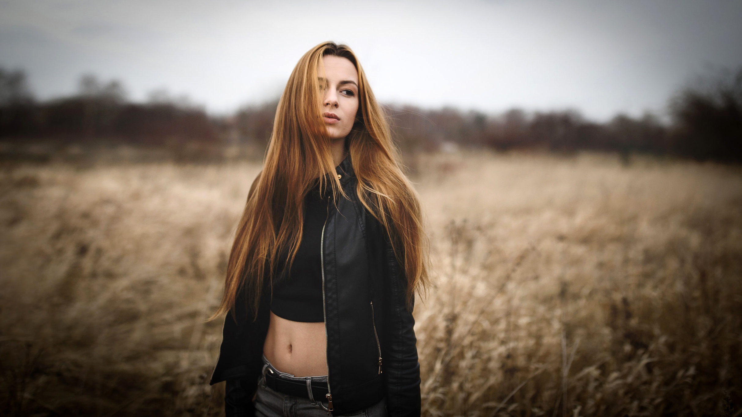Woman with long hair in a leather jacket in a field HD Wallpaper