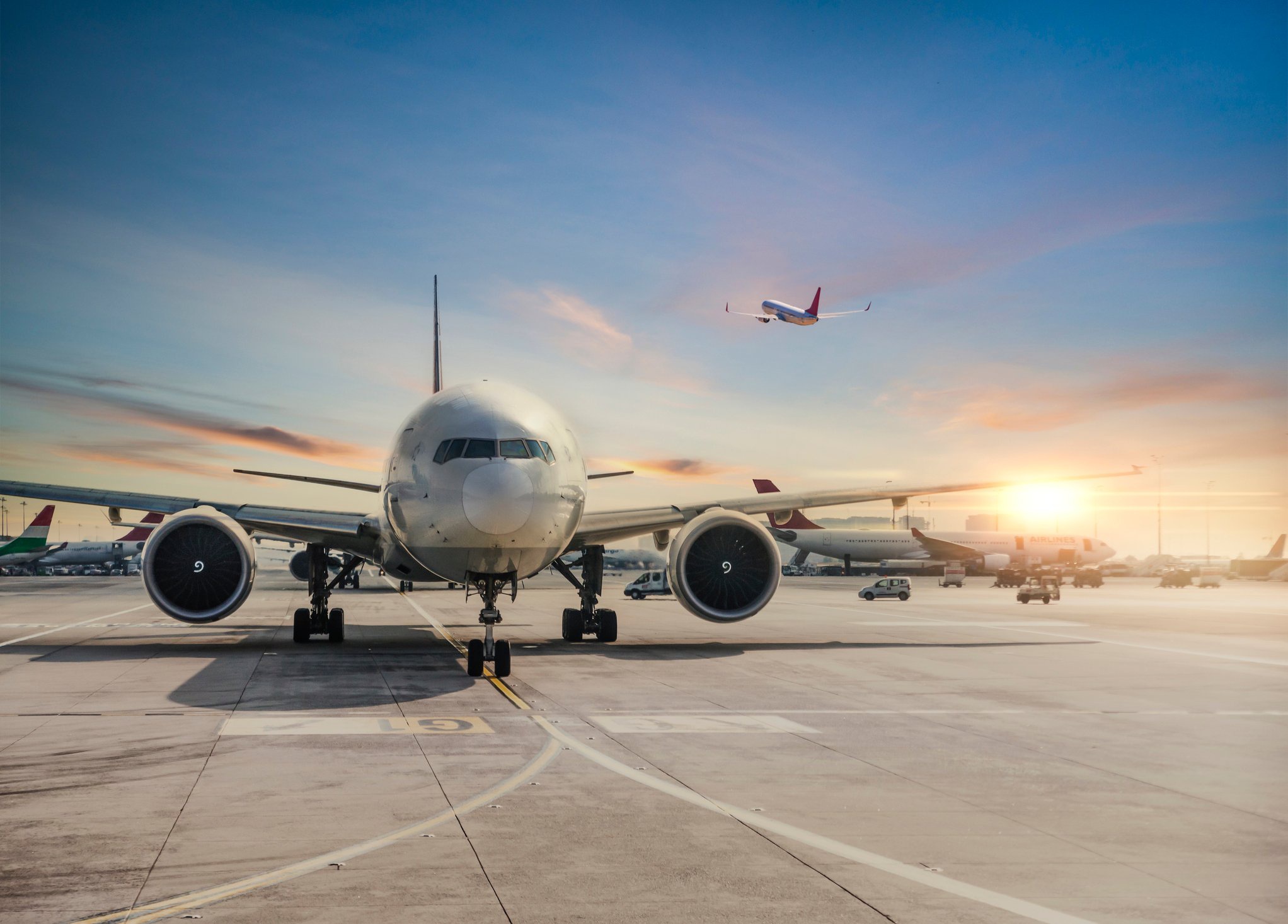 Passenger planes on airport tarmac at sunset HD Wallpaper