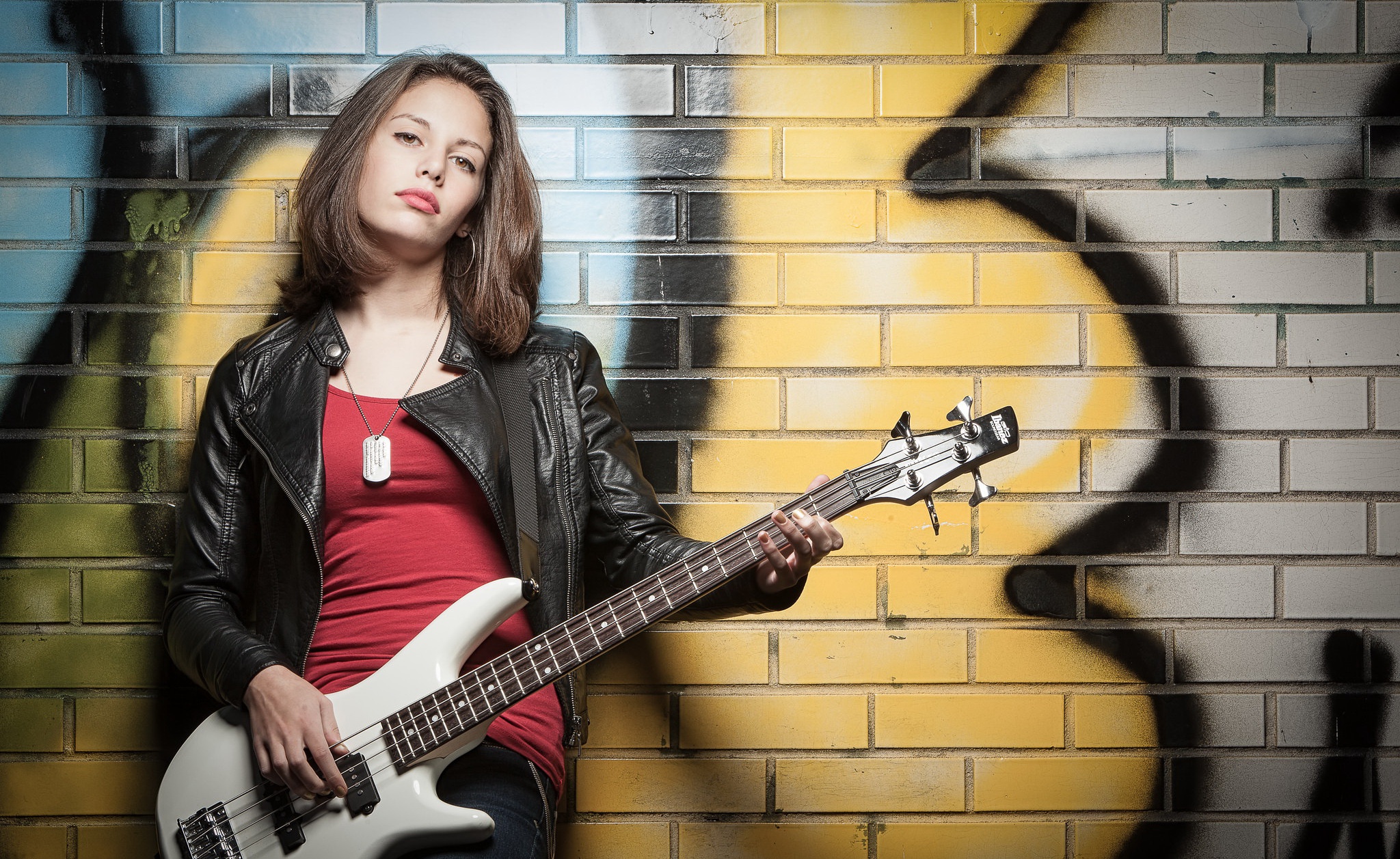 Woman in leather jacket playing bass guitar HD Wallpaper
