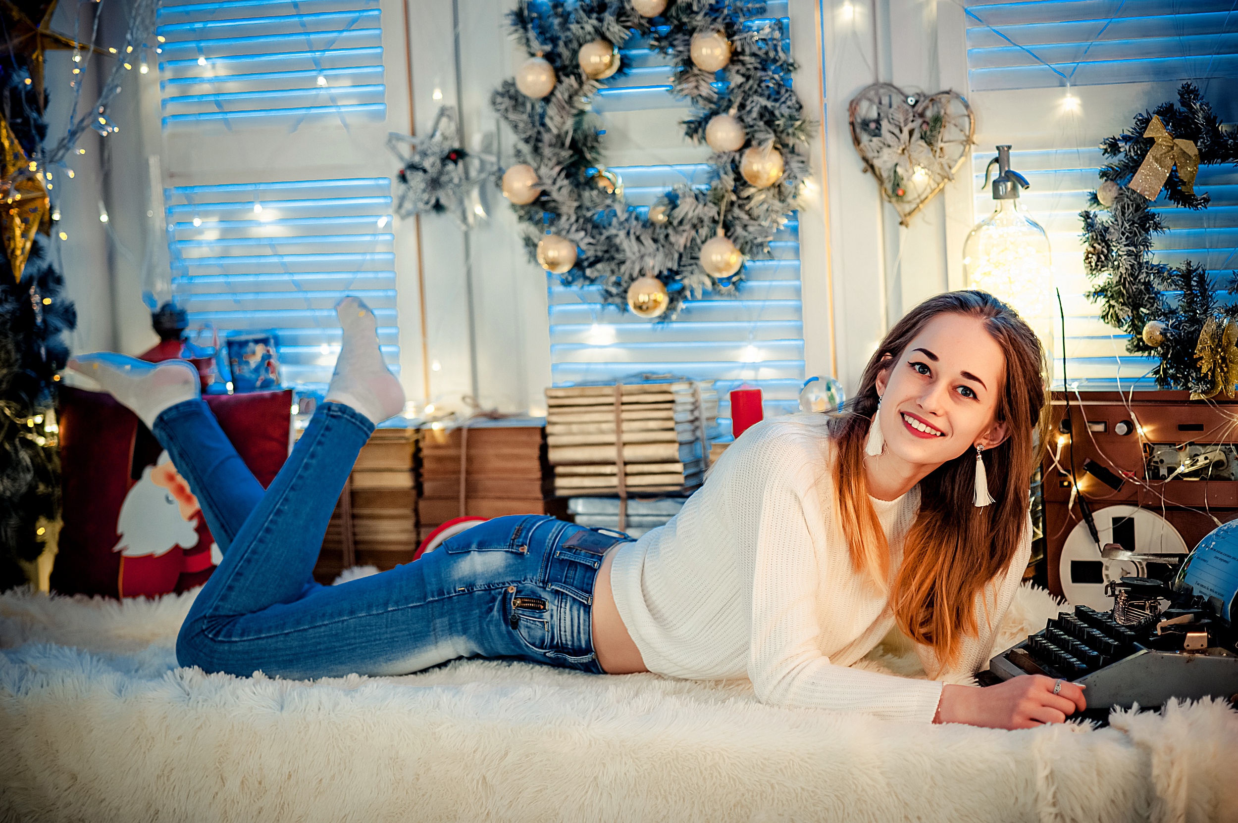 Woman in jeans and sweater lying down with Christmas decorations HD Wallpaper