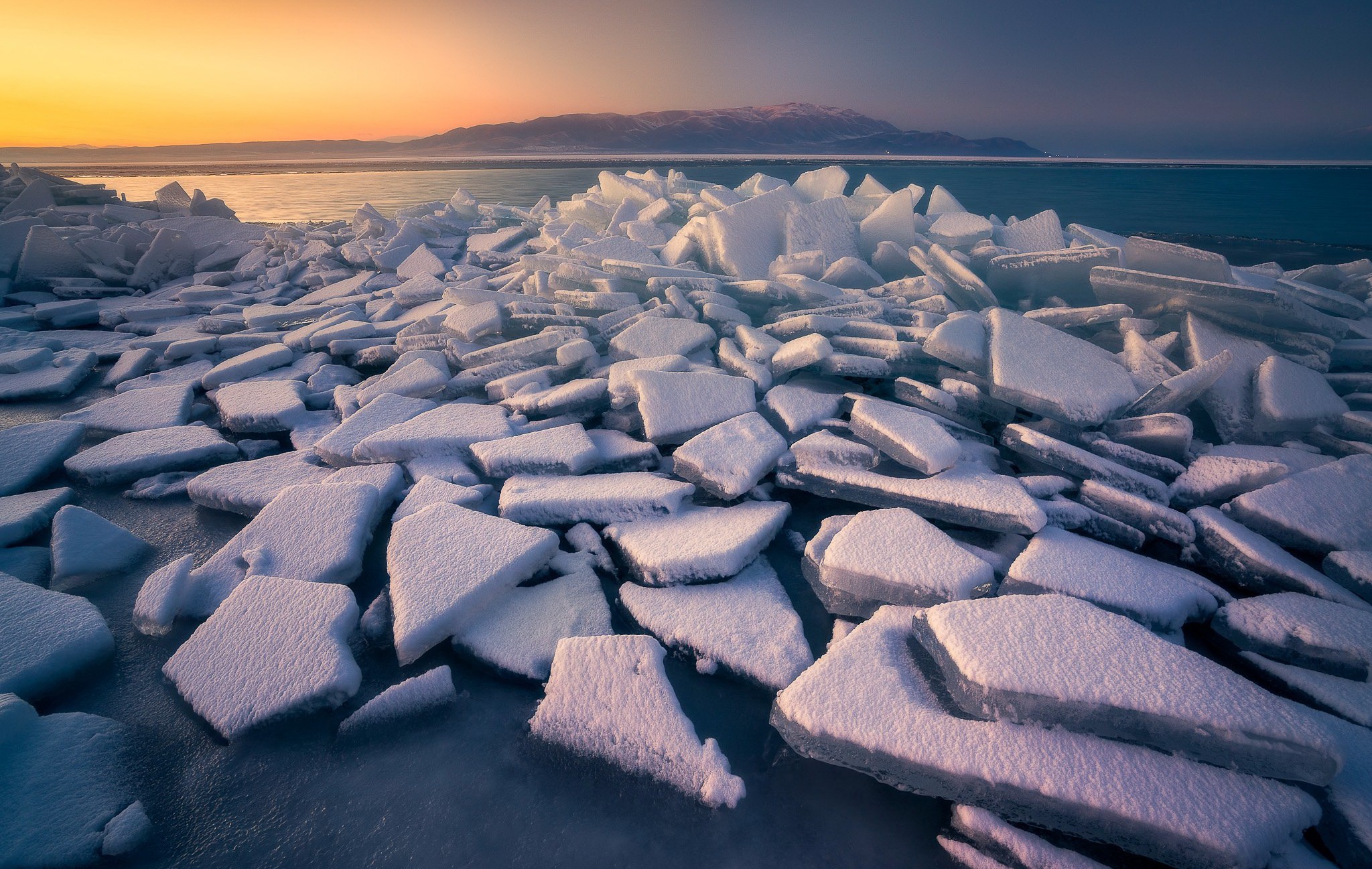 Ice chunks on a frozen lake at sunset HD Wallpaper