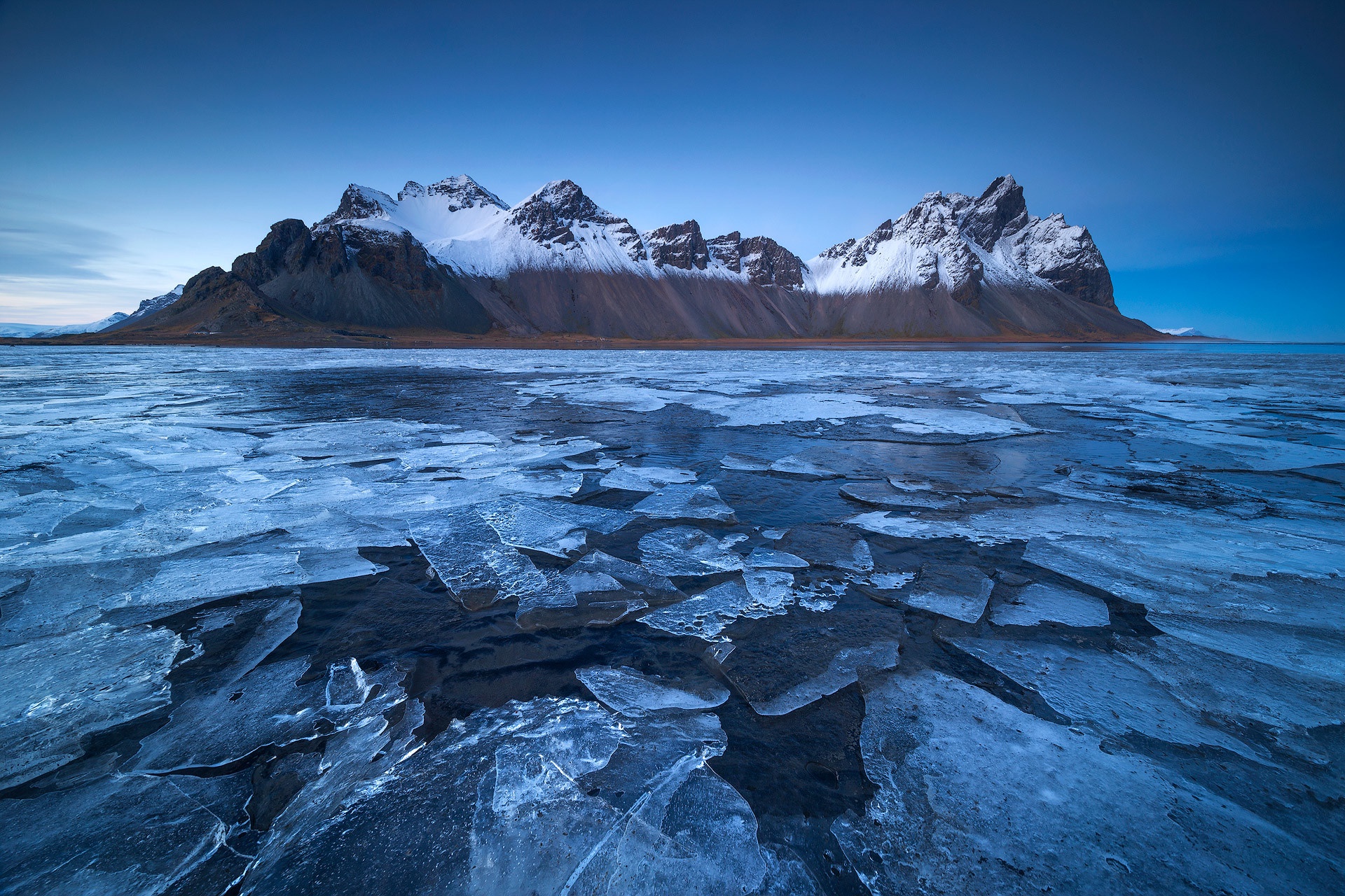 Snowy mountains by a frozen ocean HD Wallpaper