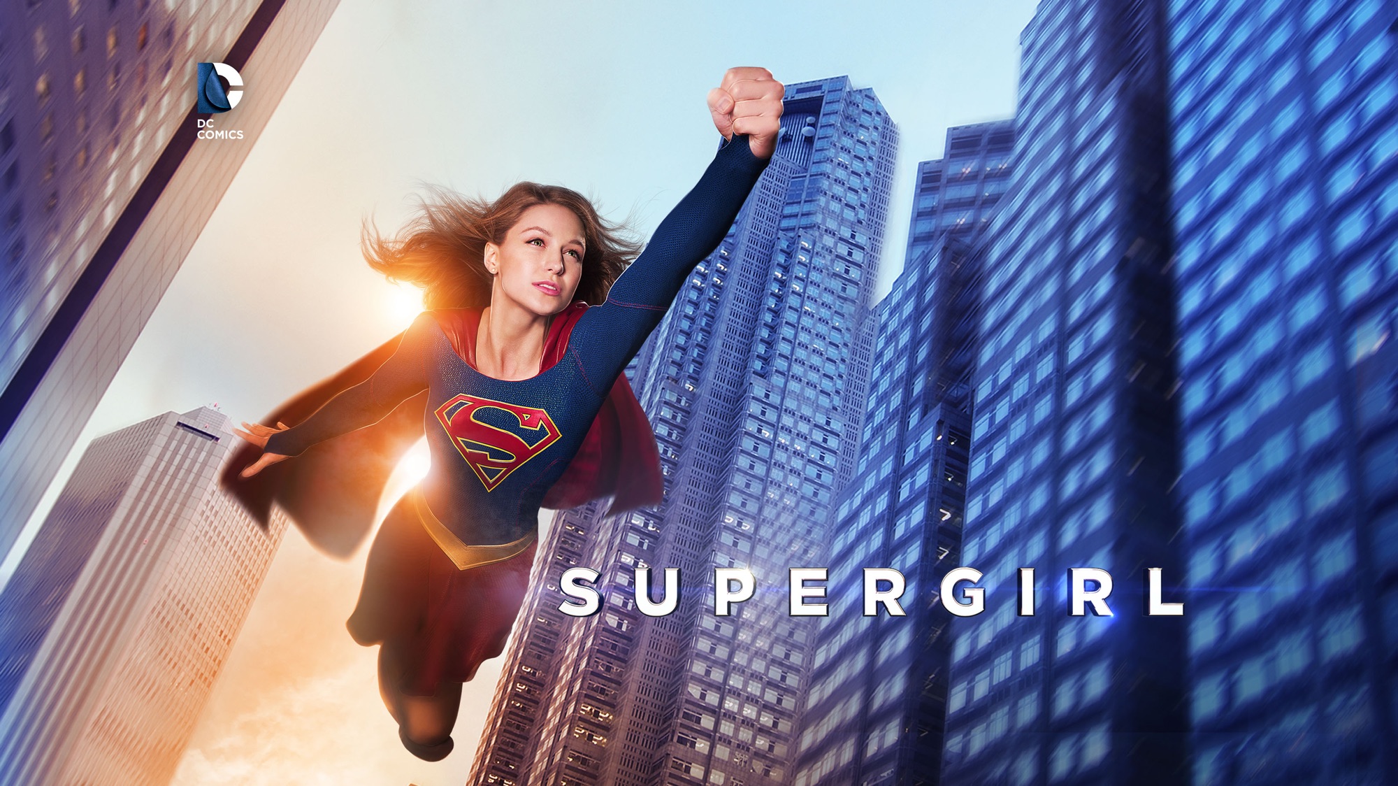 Supergirl from DC Comics flying over a city HD Wallpaper
