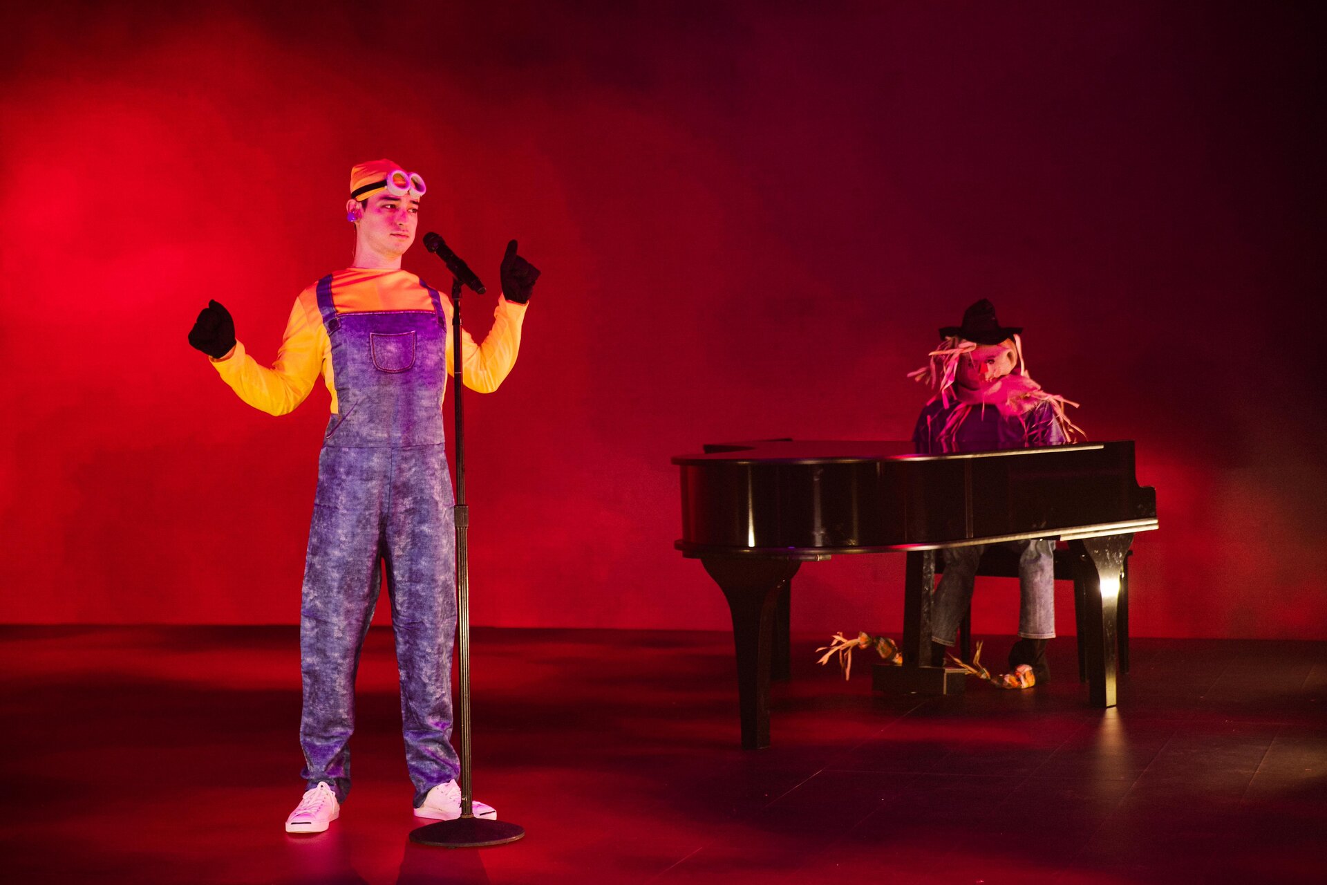 Performer in Minion costume singing on stage with scarecrow at piano HD Wallpaper